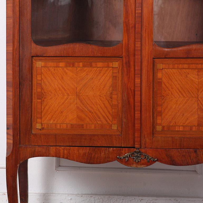 A French two-door transitional style bookcase with book-matched kingwood veneered panels with satinwood banding. The piece retains the original gilt mounts and shaped marble top. 

 