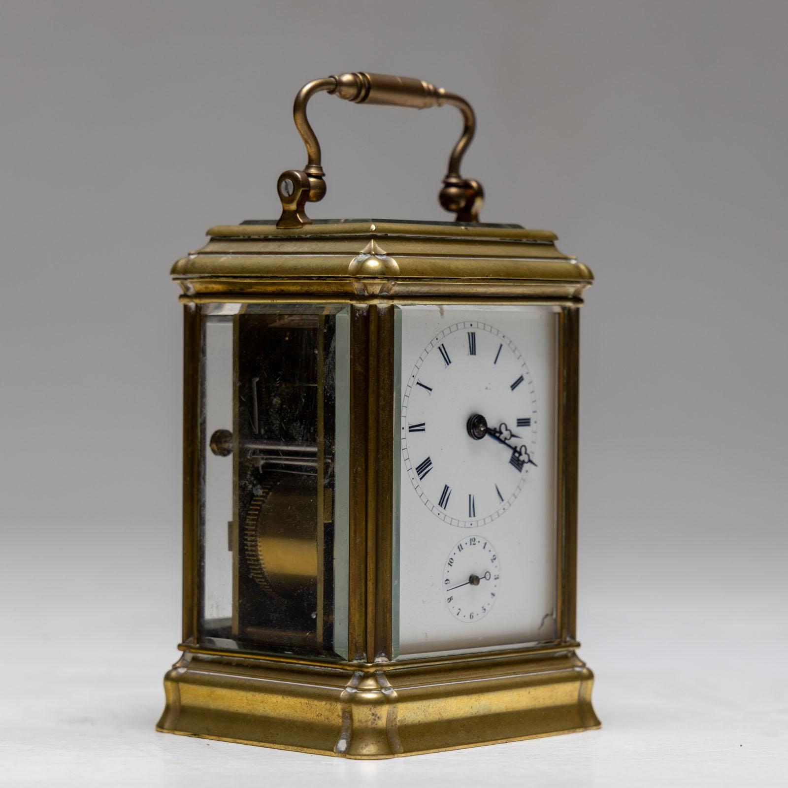 Small brass travel clock with curved handle and small profiled base. Signed Aiguilles on the movement.