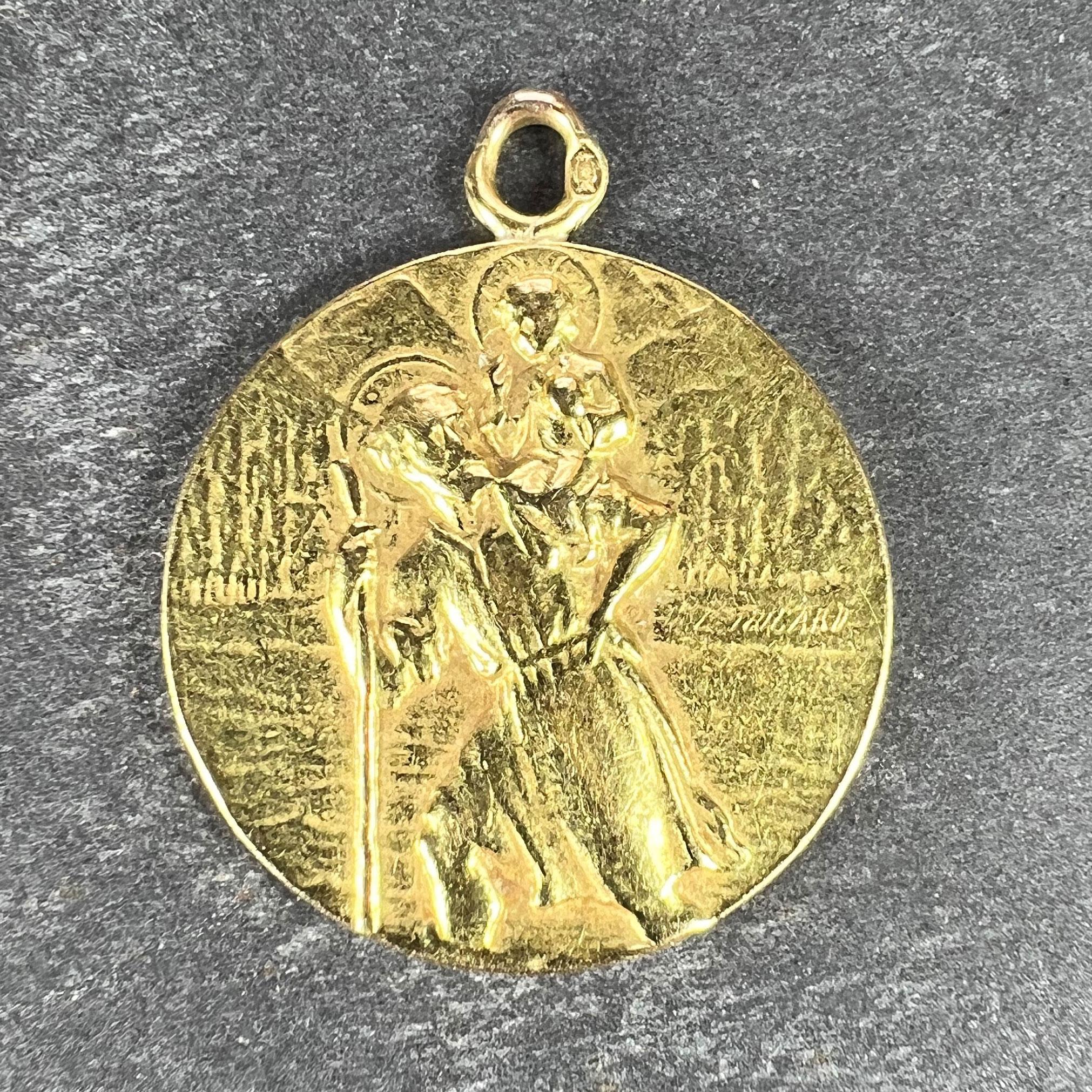 A French 18 karat (18K) yellow gold charm pendant designed as a medal depicting St Christopher as he carries the infant Christ across a river, the reverse depicting a ship in a storm with the words 'Tempestate Securitas' (Safety in the Storm) above