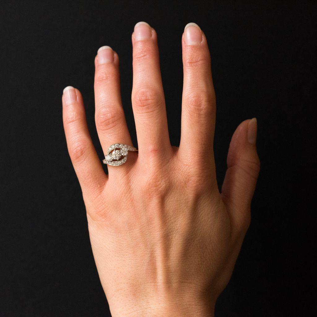 Ring aus 18 Karat Gelbgold und Platin, Hund und Adlerköpfe gestempelt. 
Dieser Ring ist mit 3 in Krallen gefassten Diamanten auf der Vorderseite versehen, die durch mit Brillanten besetzte Wirbel akzentuiert werden. 
Gesamtgewicht des mittleren