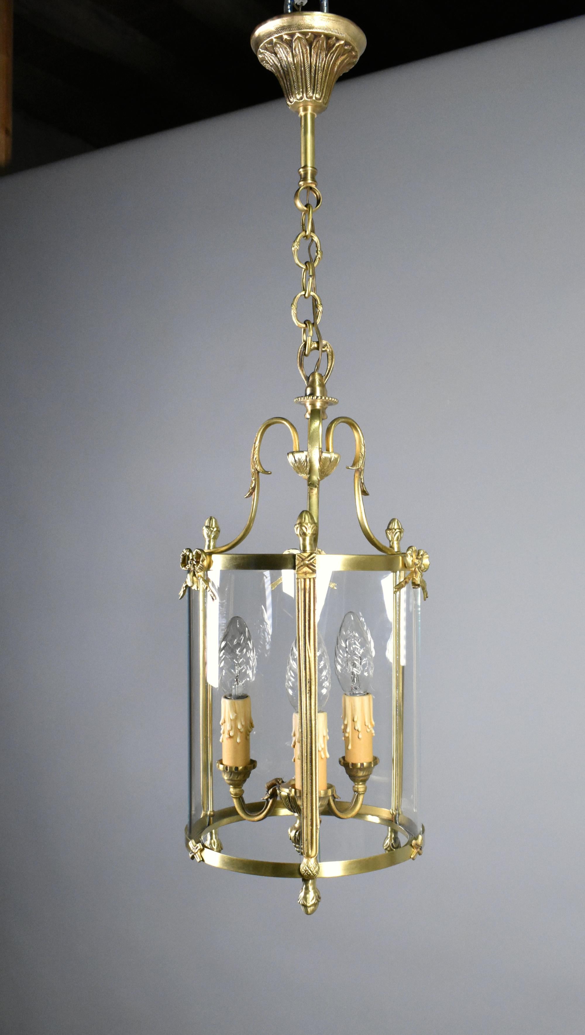 French Triple Light Hall Lantern in Bronze Louis XVI Style
 
This attractive French Hall Lantern in bronze hangs from a floral decorated ceiling rose on a chain that is adjustable according to the height needed.
 
The central stem leds down to three