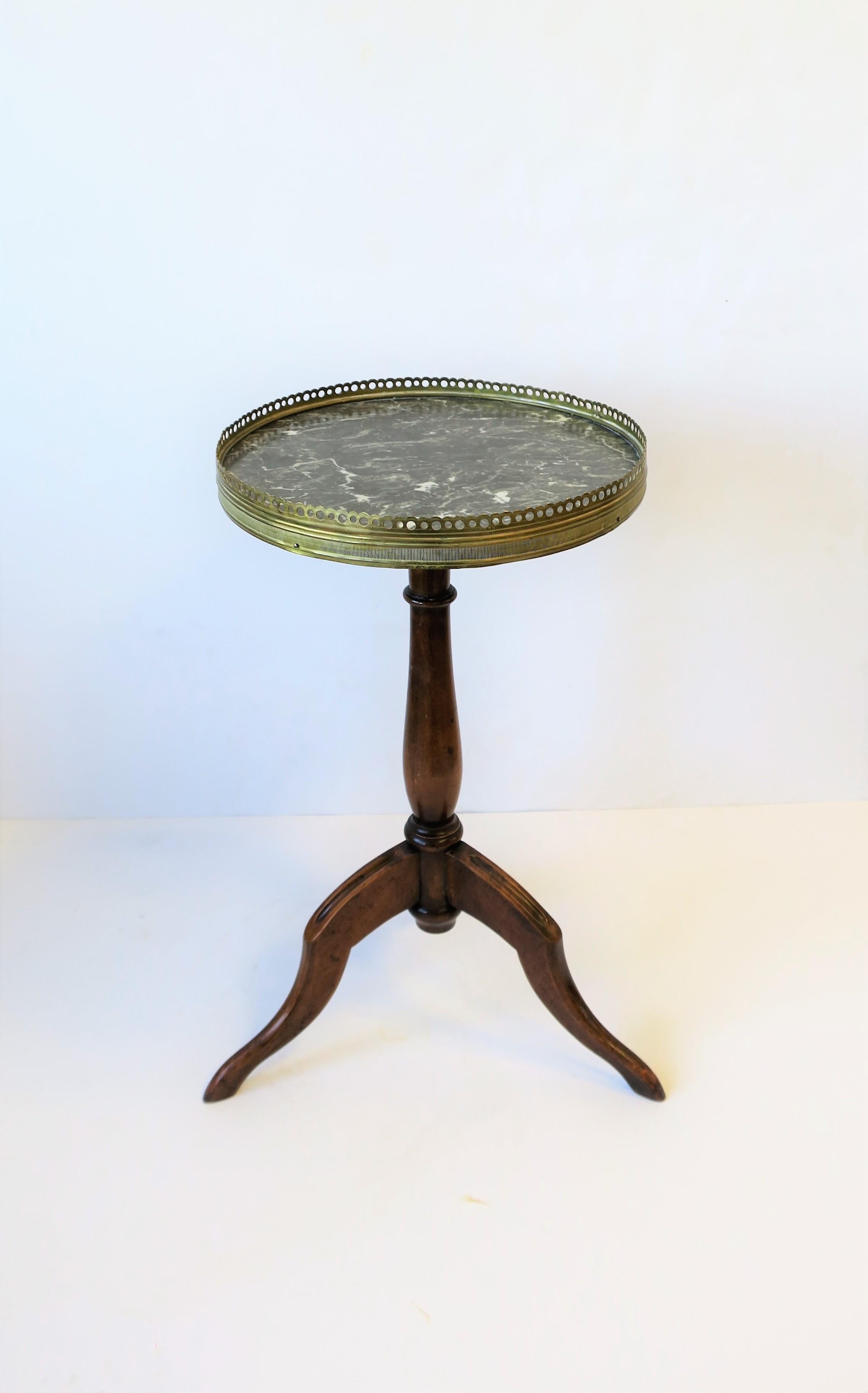 A French tripod brass, marble, and wood side or drinks table, circa Mid - Late 20th Century, France. Table has a black and white marble top, brass 'gallery' edge, and a wood tripod base. Marked 
