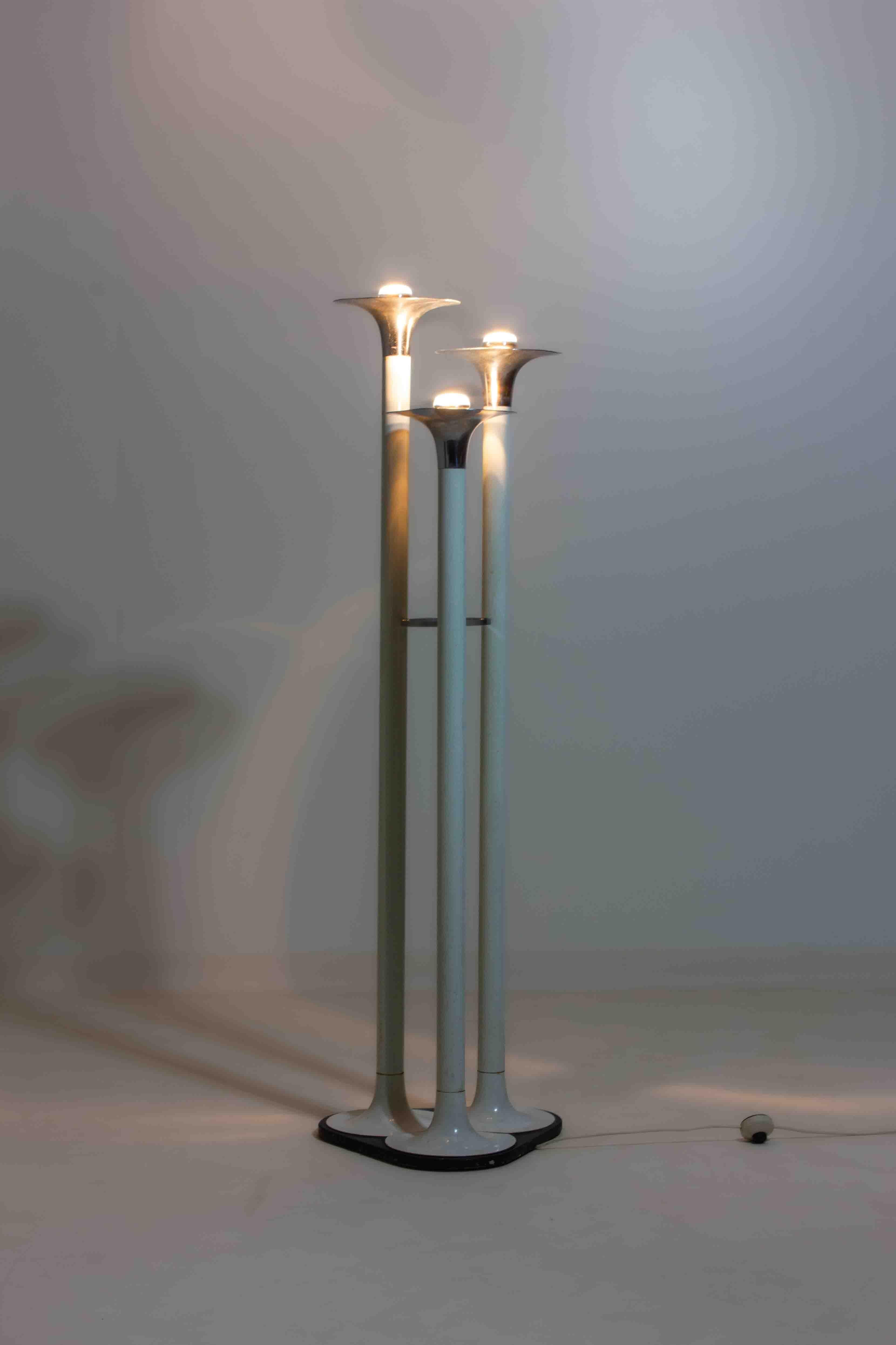 This French floor lamp from the 1970s has a simple and playful design. It stands on three tall enamelled metal tubes, each ending in a flared chrome shade that resembles a trumpet. The light shines softly upward, creating a warm glow. It’s a nice