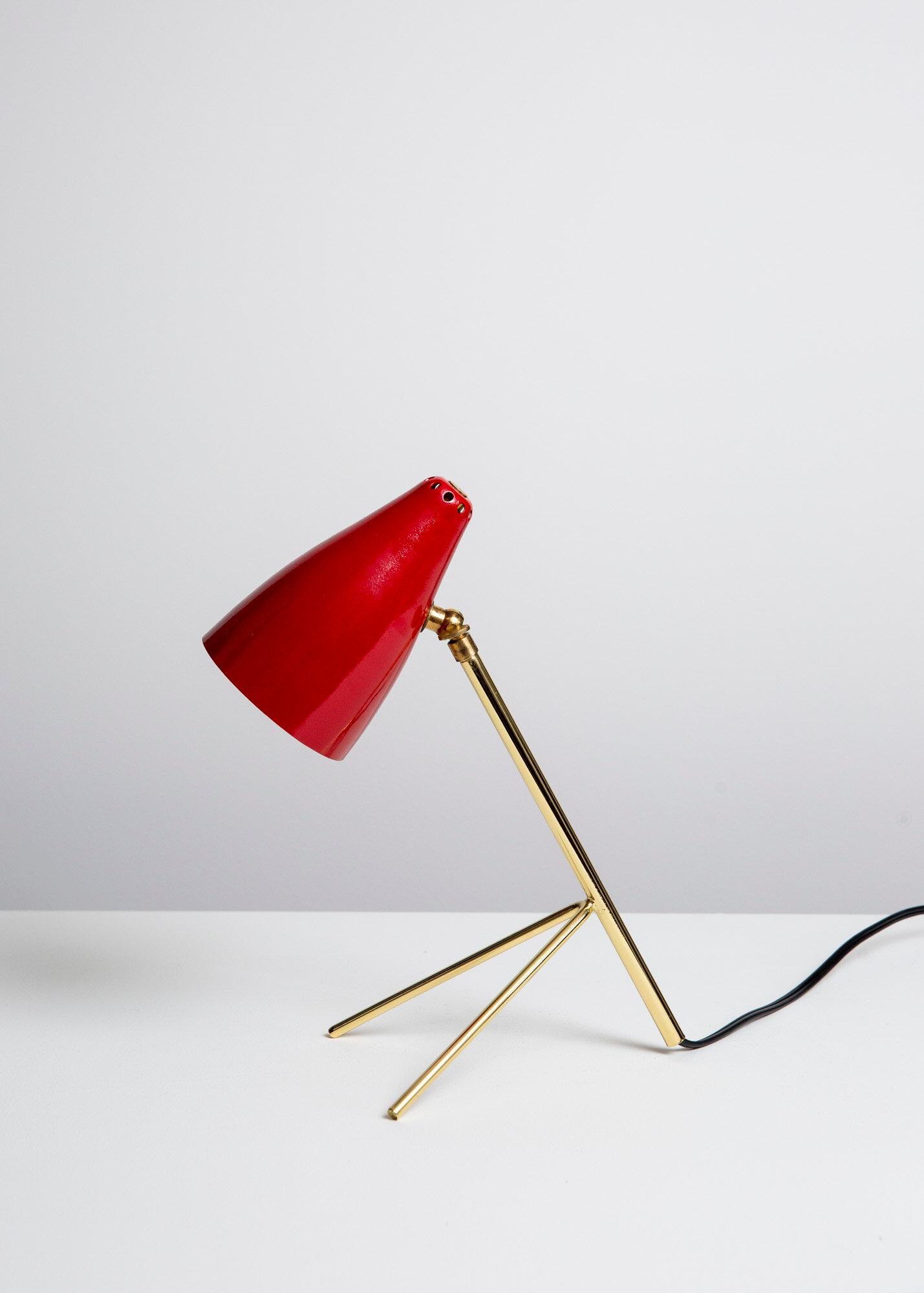 Lampe tripode française à la manière de Boris Lacroix. Abat-jour conique en aluminium percé émaillé rouge vif, pivot en laiton, tige et pied de trépied en acier plaqué laiton de type cricket. Ampoules à incandescence G-16.5 candélabres de 40 watts