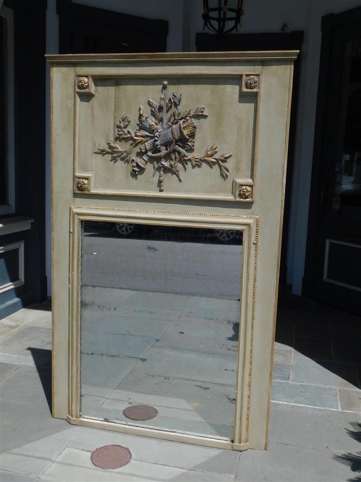 French Trumeau painted and gilt carved wood gesso wall mirror with quiver of arrows, tassels, intertwined foliage torchieres, gilt bead work, and flanking gilt corner medallions. Mirror retains the original silvered glass and wood backing. Late 18th