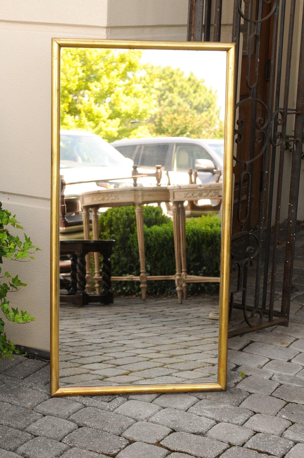 A French giltwood rectangular wall mirror from the early 20th century, with clear mirror plate. Born in France during the turn of the century, this elegant wall mirror features a simple rectangular frame, made of rounded giltwood edges. Surrounding