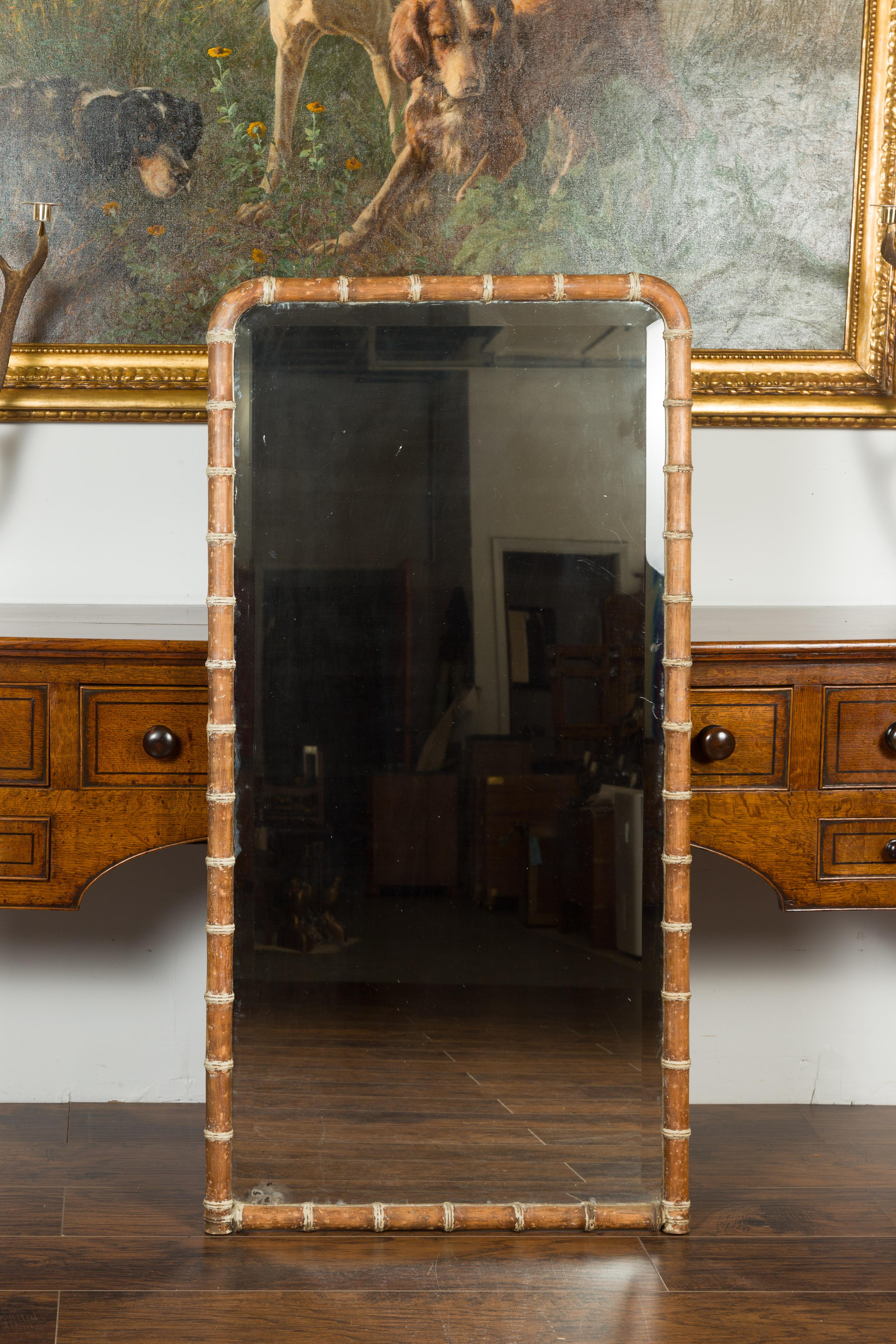 A French walnut faux bamboo mirror from the turn of the century, with Louis-Philippe silhouette. Created in France during the early years of the 20th century, this faux bamboo mirror features a linear frame with rounded corners at the top,