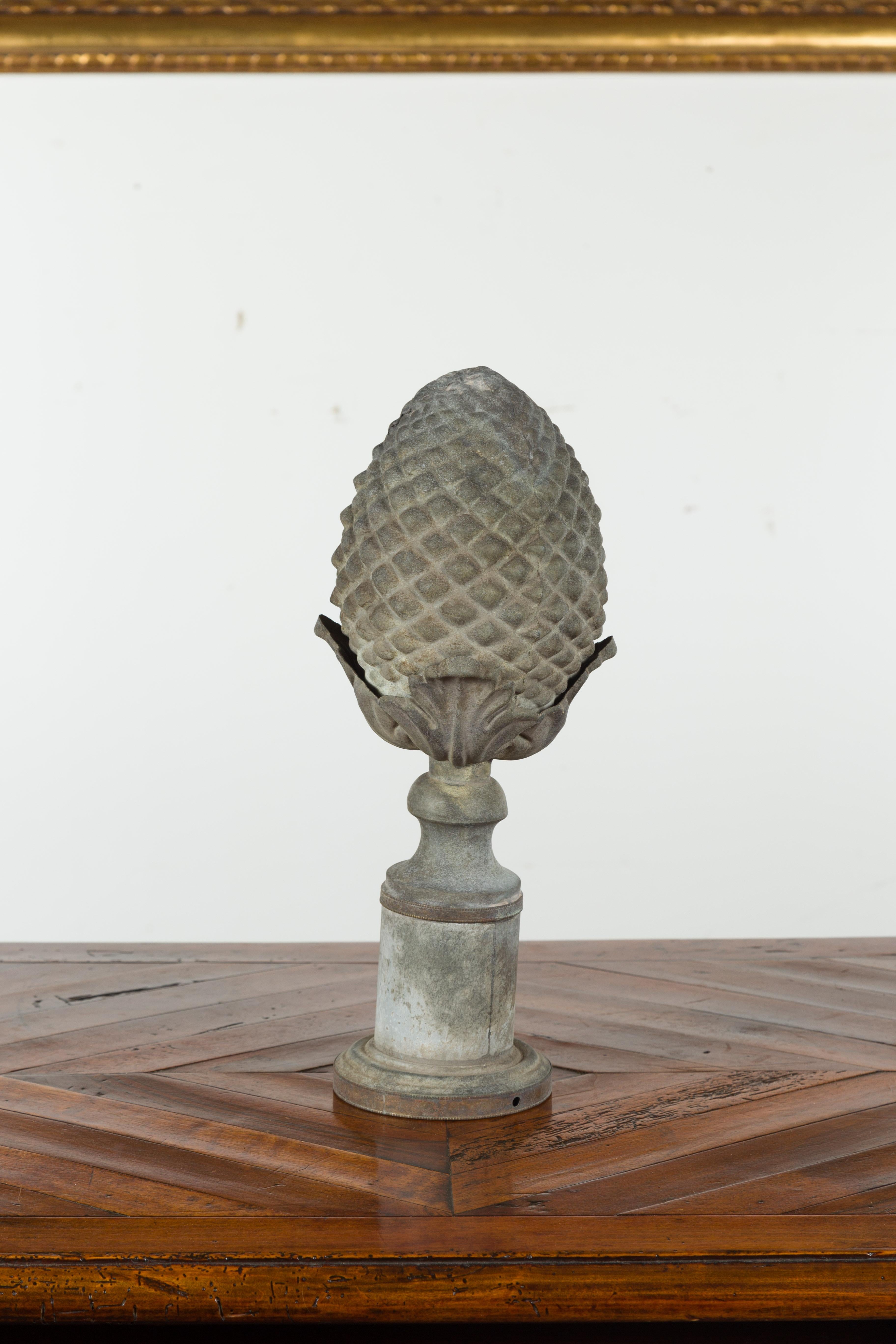 A French zinc pinecone fragment from the early 20th century, with acanthus leaves and tall circular base. Created in France during the turn of the century, this zinc fragment depicts a large pinecone emerging from handsome acanthus leaves. Raised on