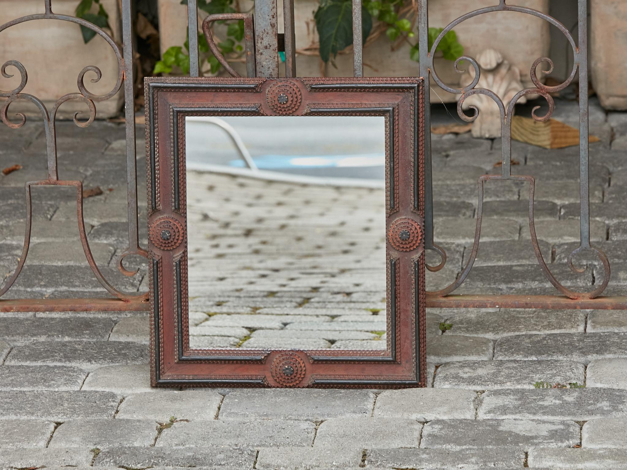 A French Turn of the Century brown and black Tramp Art mirror from circa 1900 with raised circular medallions. Embark on a journey through time with this captivating French Turn of the Century brown and black Tramp Art mirror from circa 1900. Its