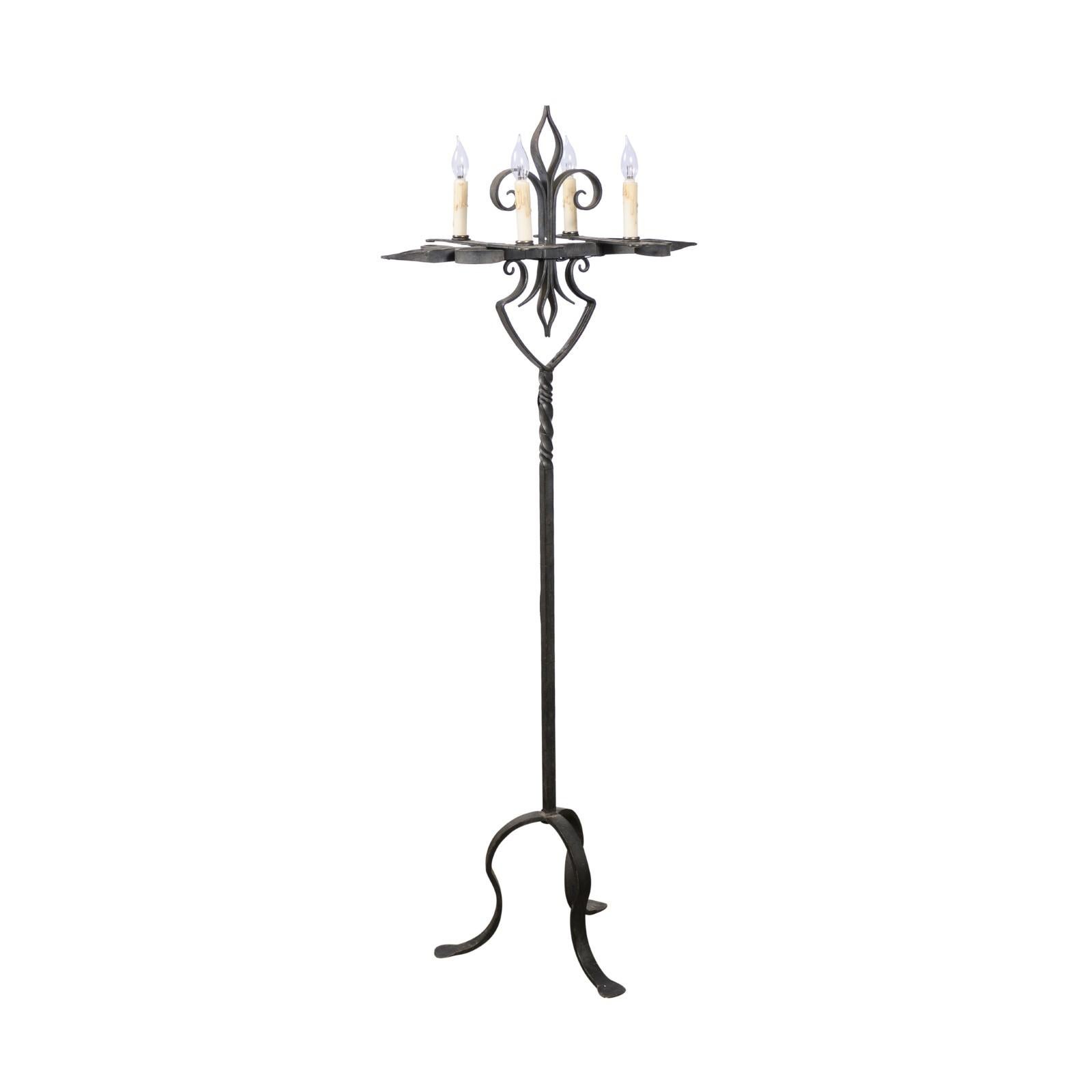 A French Turn of the Century candelabra style wrought-iron four-light floor lamp from the early 20th century, with fleur-de-lys motifs, twisted accents and tripod base. Created in France during the early years of the 20th century, this floor lamp,