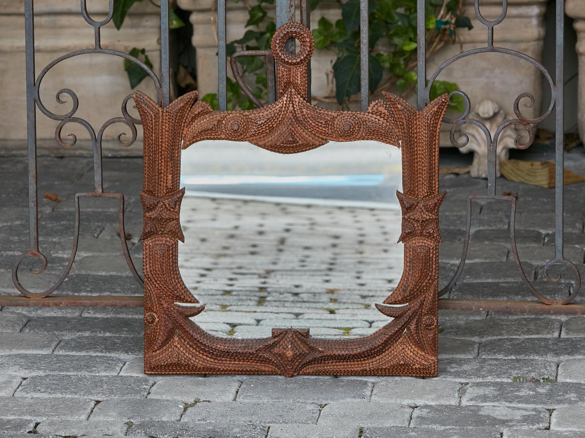A French Tramp Art carved wooden mirror from the Turn of the Century with unusual shape. This exceptional French Tramp Art carved wooden mirror, dating back to the Turn of the Century, circa 1900, is a stunning testament to artisan craftsmanship.