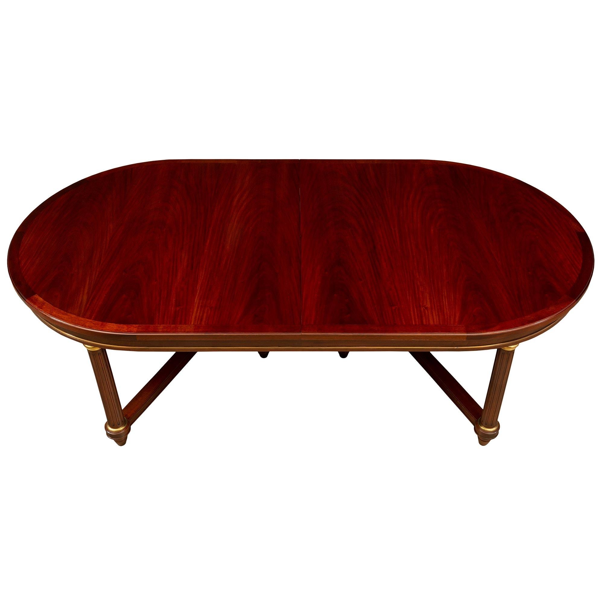 A striking and very elegant French turn of the century Empire st. flamed Mahogany and ormolu dining table. The table is raised by six elegant and impressive lightly tapered circular fluted columns with fine topie shaped feet each connected by a most