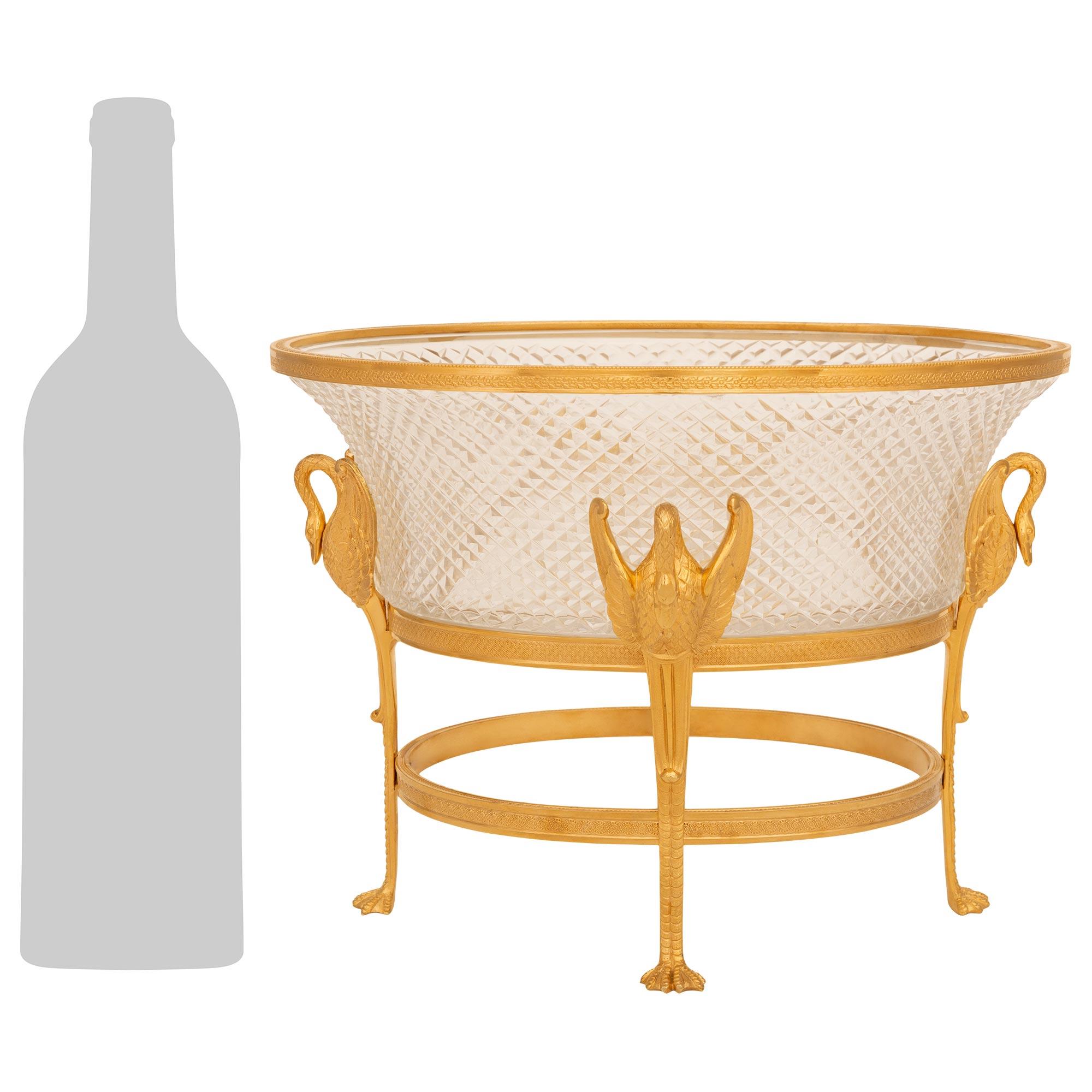 An elegant and finely detailed French Turn of the Century Empire st. Ormolu and Crystal centerpiece. The stunning cut Crystal bowl is raised on four straight legs displaying clawed feet and leading to open winged swans with curved necks. Each leg is