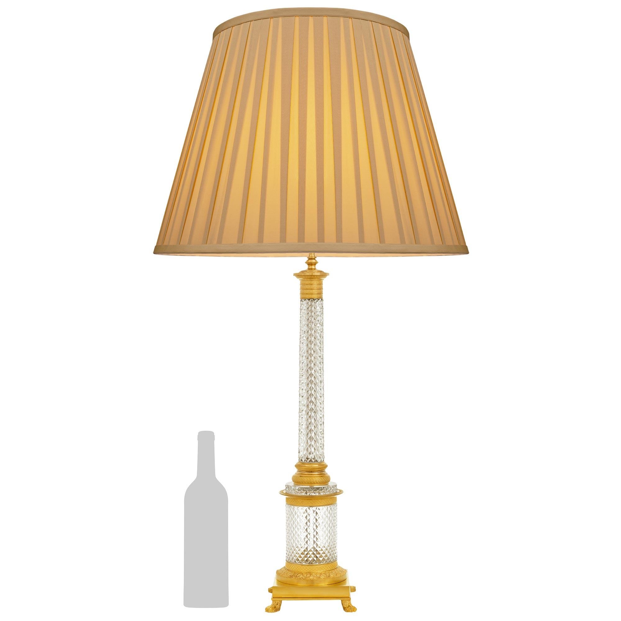 A handsome and high quality French Turn of the Century Empire st. Ormolu and Crystal lamp. This stunning lamp is raised on Ormolu pawed feet below the square base with a foliate designed band below the circular diamond cut Crystal pedestal. At the