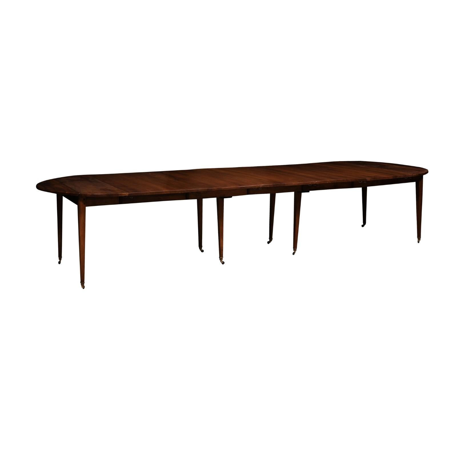 A French Turn of the Century walnut oval extension dining room table from circa 1900, with five leaves, tapered legs and casters. This exquisite French Turn of the Century walnut dining table, circa 1900, masterfully combines historical charm with