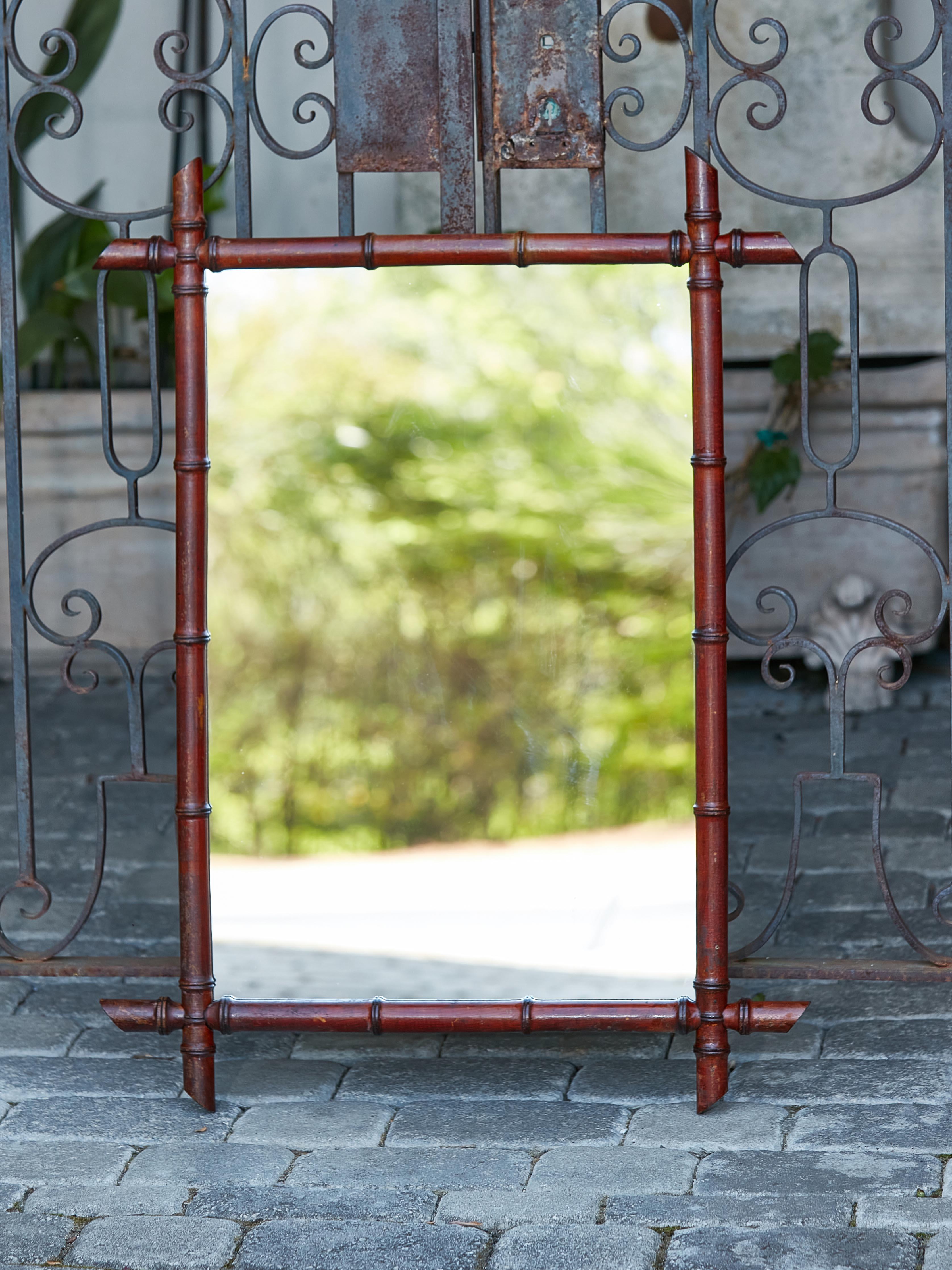A rustic French Turn of the Century faux-bamboo mirror from circa 1900 with intersecting corners and slanted accents. Introducing a delightful piece of rustic French charm, this Turn of the Century faux-bamboo mirror, circa 1900, weaves an aura of