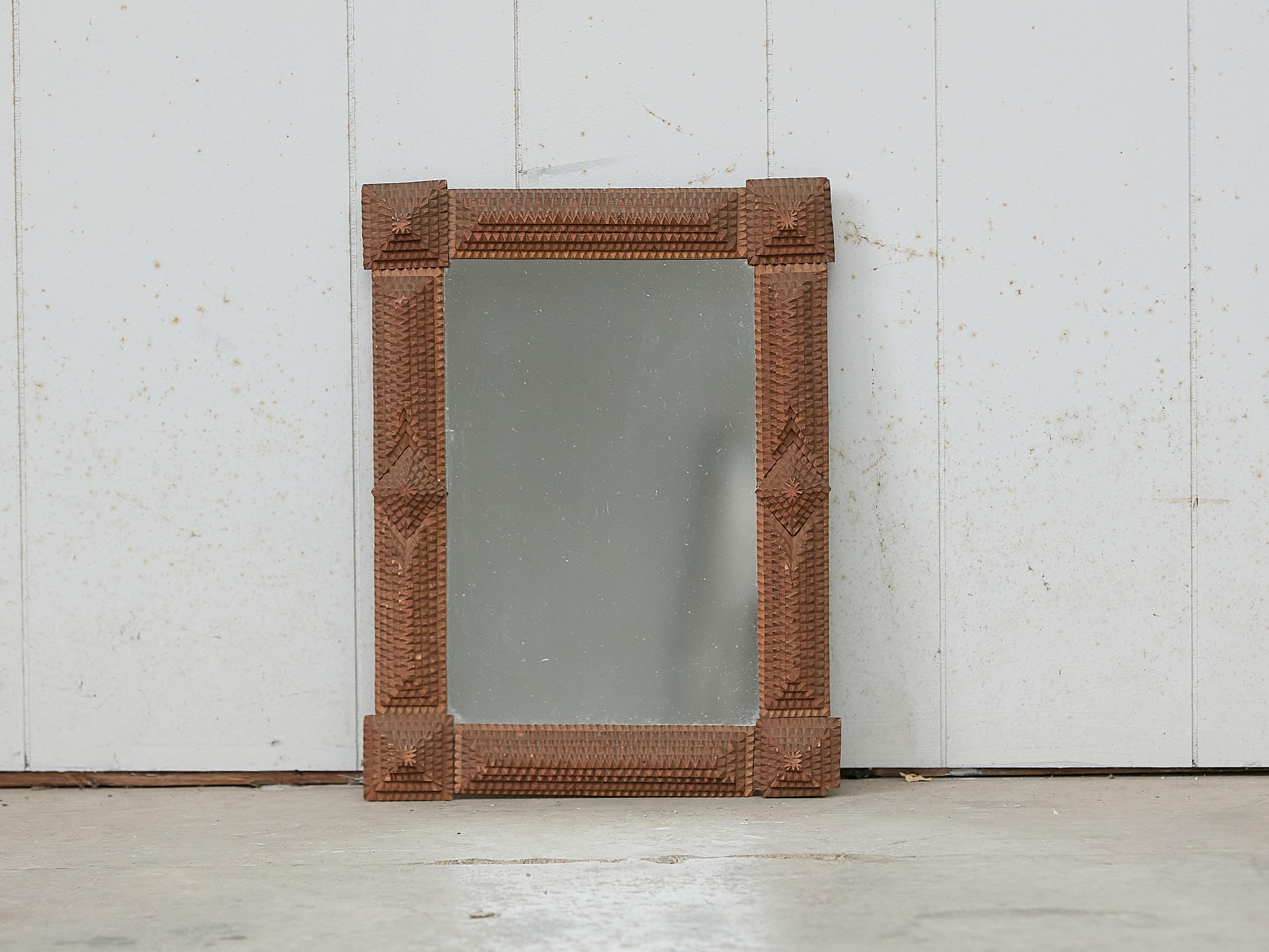 A small French Tramp Art hand carved wooden Folk mirror from the early 20th century with raised diamond motifs and protruding corners. Created in France during the Turn of the Century which saw the transition between the 19th to the 20th, this Folk