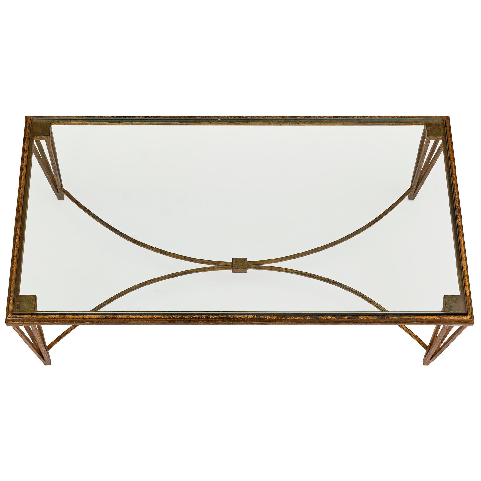An elegant and most decorative French Turn of the century Louis XVI st. gilt iron and glass coffee table by Maison Ramsey. The coffee table is raised by beautiful pierced tapered legs each displaying four unique square supports and connected by a