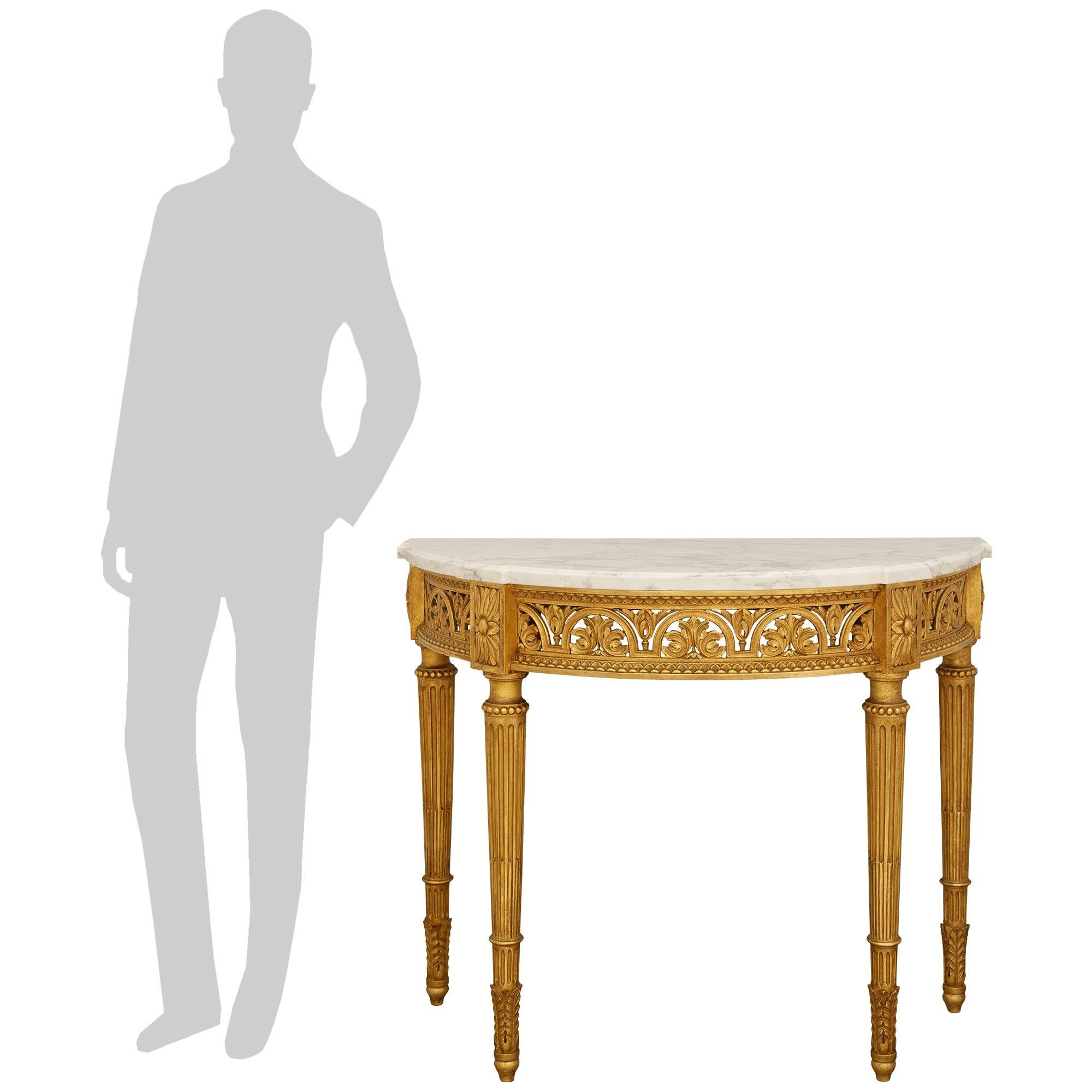 An elegant and high quality French Turn of the Century Louis XVI st. Giltwood and white Carrara marble console. This wonderful freestanding console is raised on four circular fluted and tapered legs displaying acanthus leaf feet leading to mottled