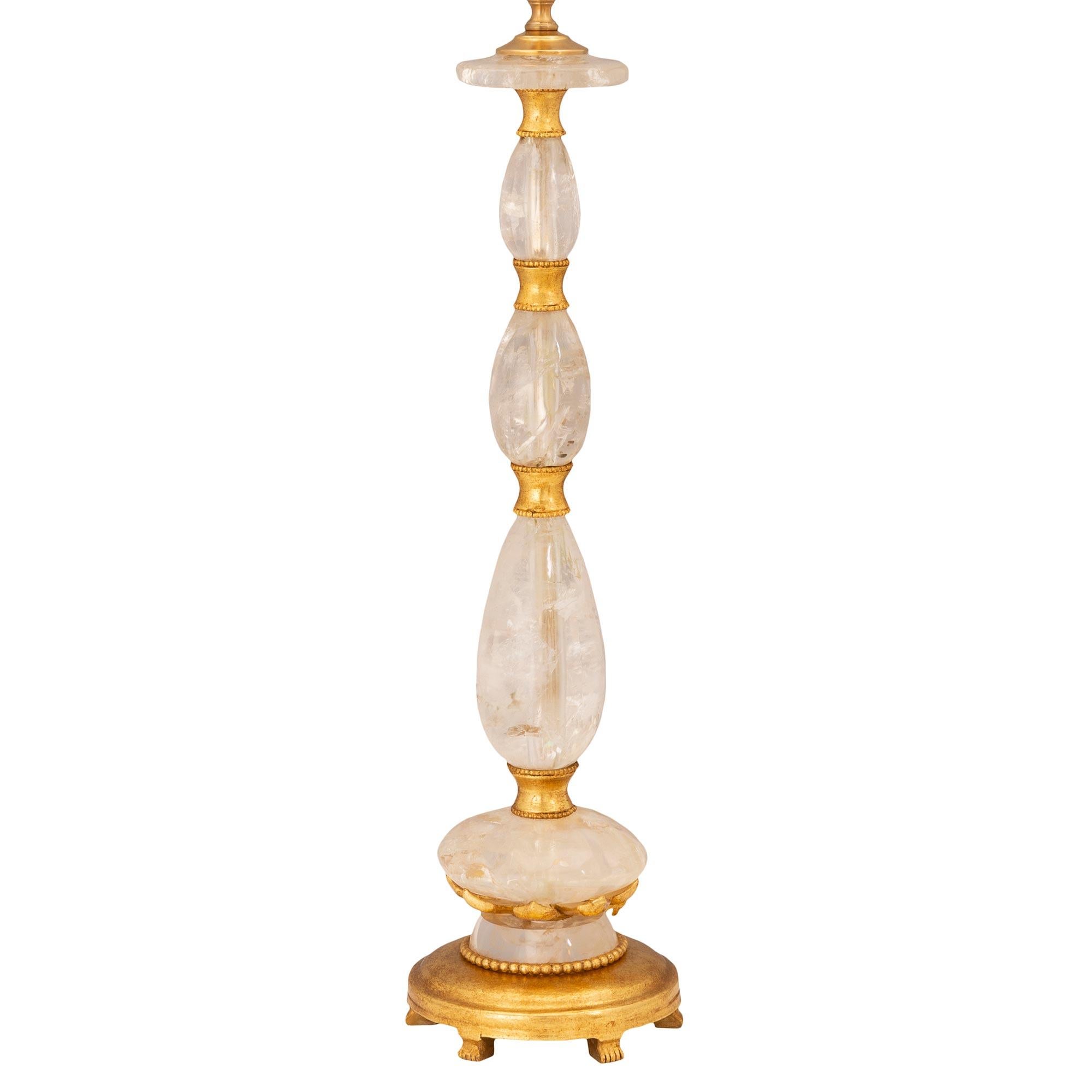 An exceptional French turn of the century Louis XVI st. giltwood, gilt metal, and rock crystal lamp. The lamp is raised by an elegant circular mottled giltwood base with six unique and most decorative fluted feet and a wrap around beaded band. The