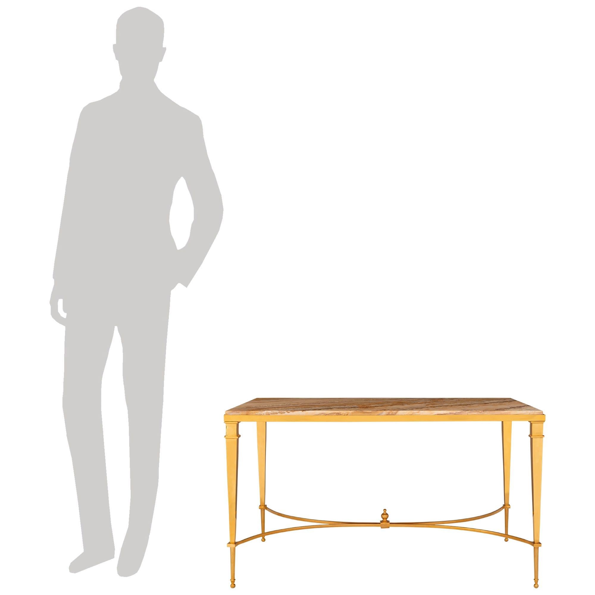 Une élégante et très décorative table basse en bronze doré et onyx du début du siècle, attribuée à Mason Bagues. Cette belle table basse rectangulaire repose sur quatre pieds fuselés en bronze doré, soutenus par des pieds en forme de boule. Les