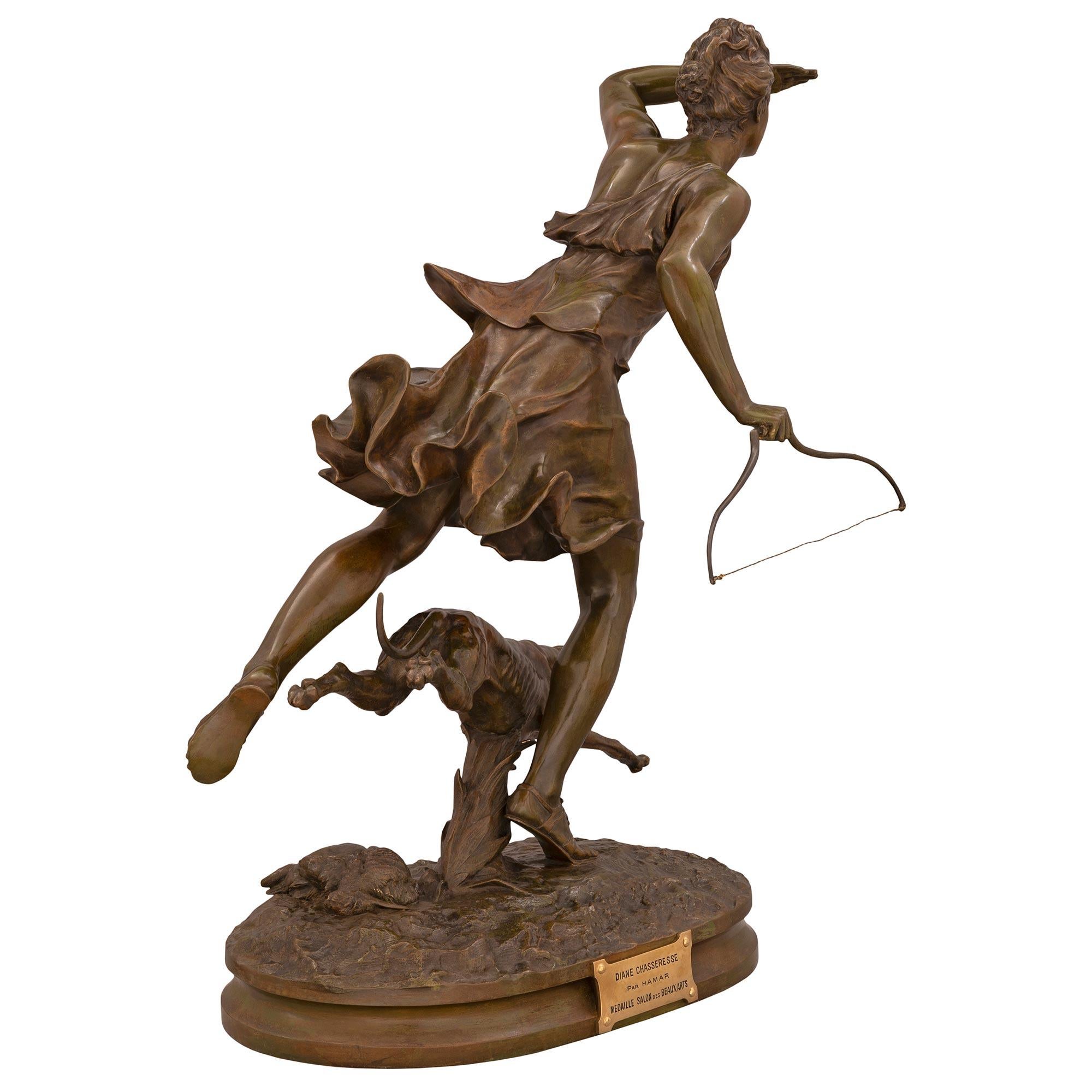 Eine atemberaubende französische Statue aus patinierter Bronze und Ormolu von Diana der Jägerin und ihrem Hund, signiert F. Hamar, aus der Jahrhundertwende. Die Statue steht auf einem eleganten, länglichen Sockel mit einer fein gesprenkelten