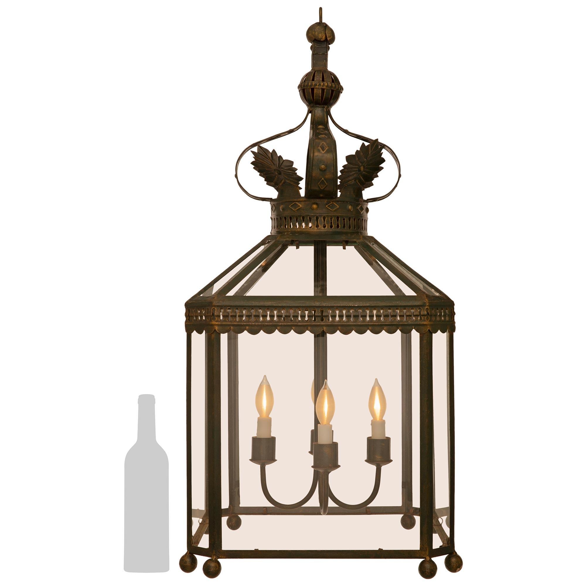 A handsome and most decorative French Turn of the Century Louis XVI st. Wrought Iron lantern. The octagonal four arm four light lantern consist of an eight sided cage with bottom spheres below each corner. Along the top edge is a scalloped Iron band
