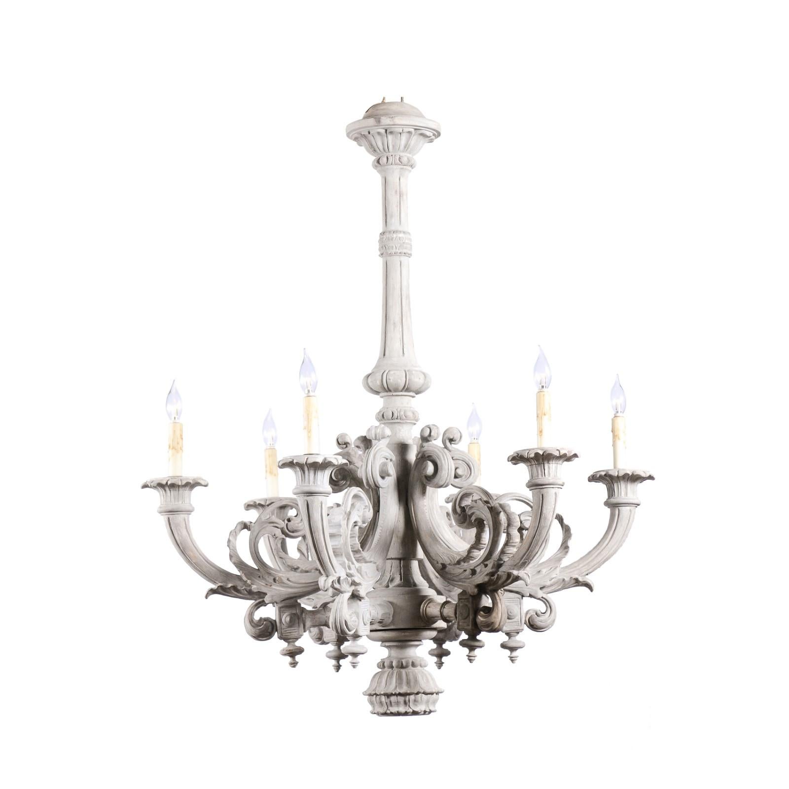 A French Turn of the Century wooden chandelier from the early 20th century, with six lights, richly carved décor, C-scroll arms and rustic wash painted finish. Created in France at the Turn of the Century in the 1900s, this wooden chandelier