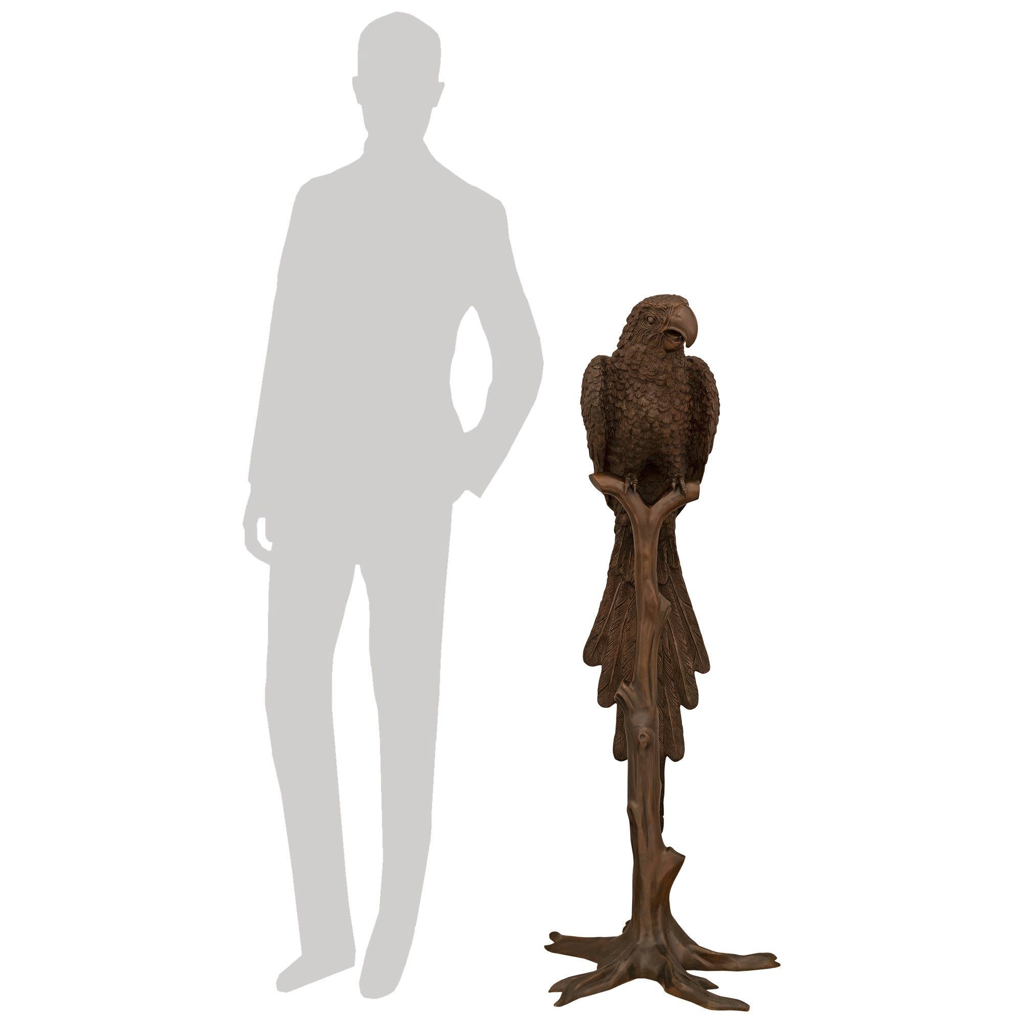 Una meravigliosa e finemente dettagliata statua in bronzo patinato francese di fine secolo raffigurante un pappagallo. Questa graziosa statua di un pappagallo appollaiato su un albero è sostenuta da una base a forma di radice con cinque piedi