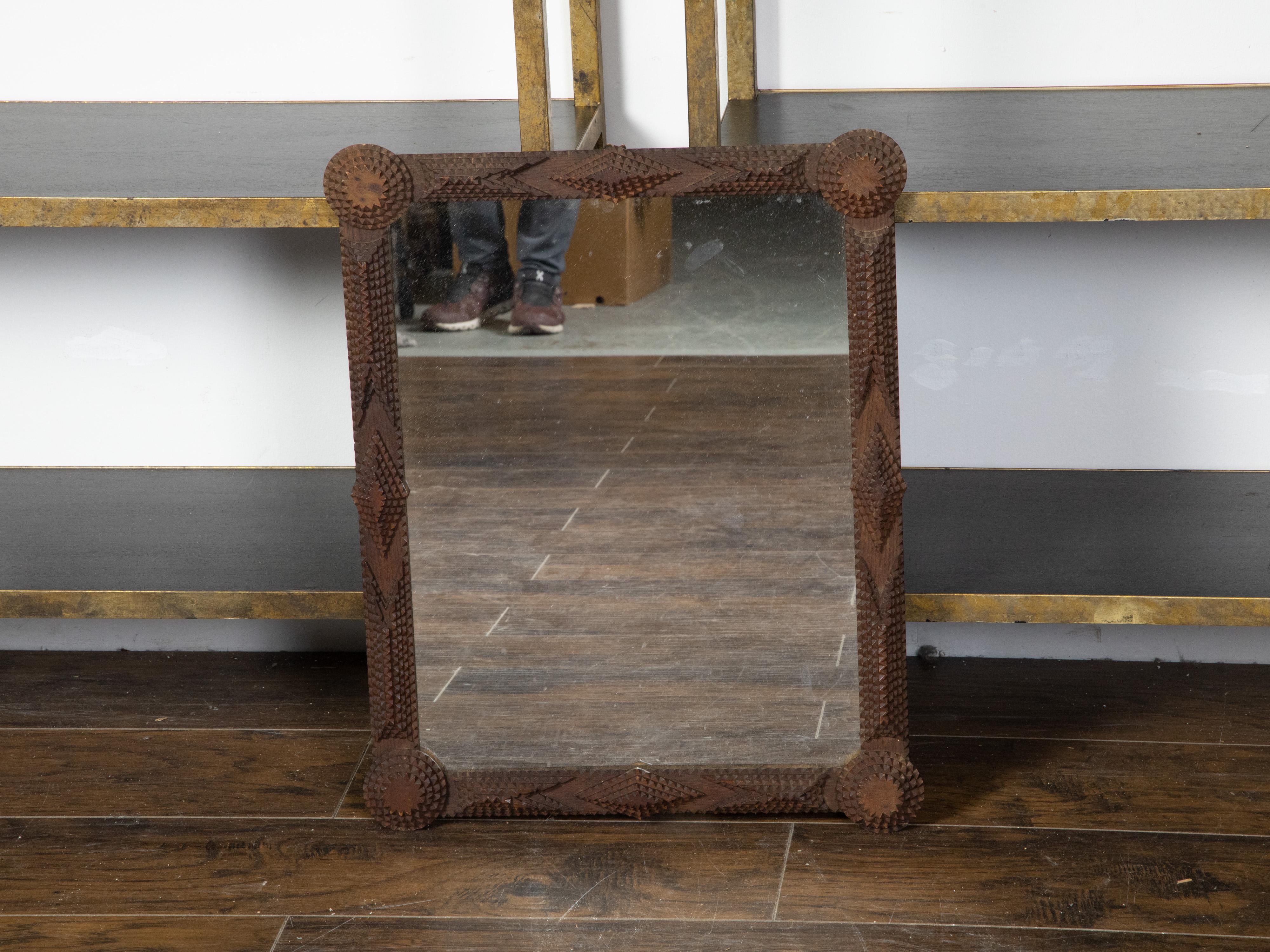 A French Tramp Art hand-carved mirror from the Turn of the century, with rounded corners and pyramidal raised motifs. Created in France during the early years of the 20th century, this wall mirror was hand carved in the manner typical of the Tramp