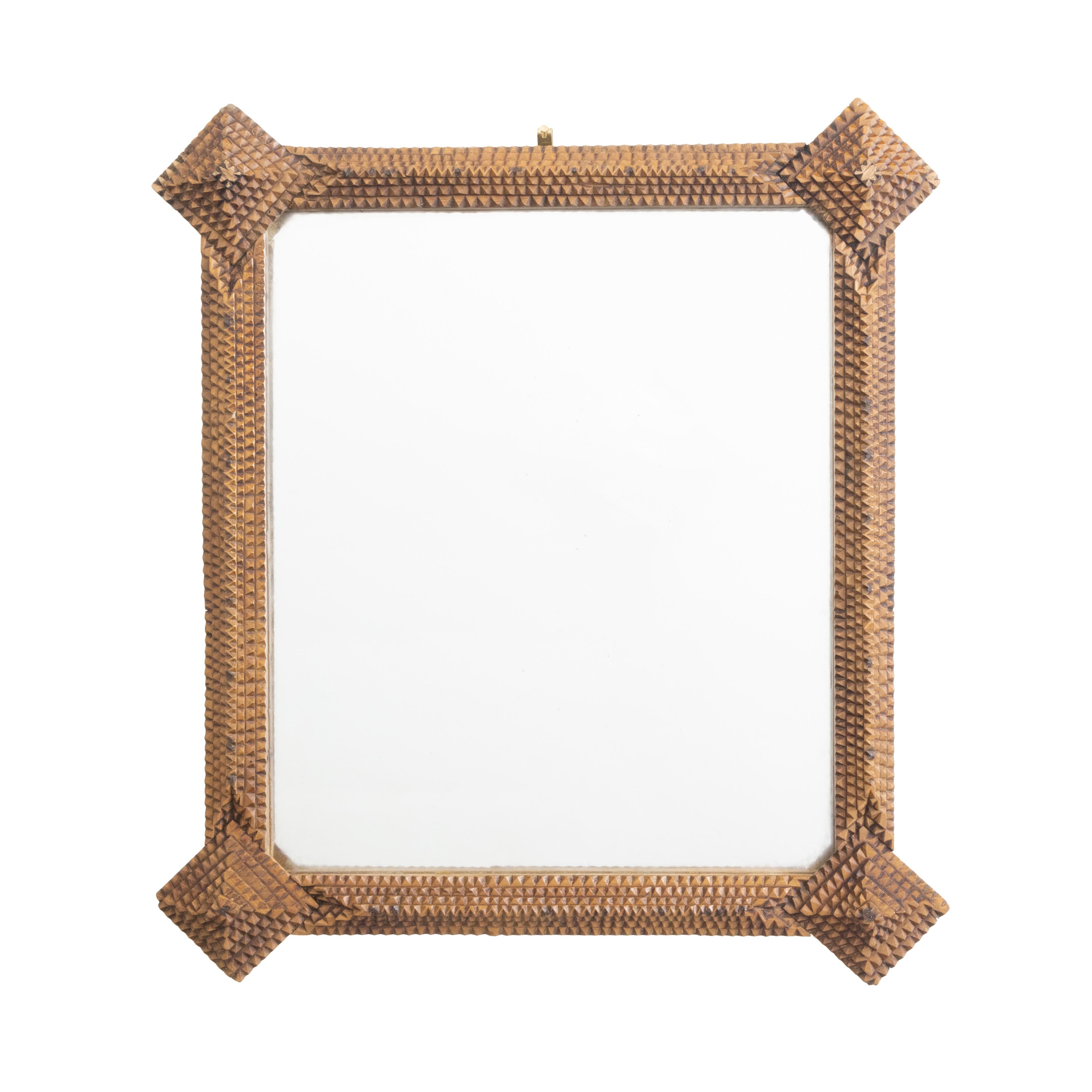 A French Tramp Art hand carved mirror from the Turn of the century, with pyramidal motifs in the corners. Created in France during the early years of the 20th century, this wall mirror was hand carved in the manner typical of the Tramp Art style.