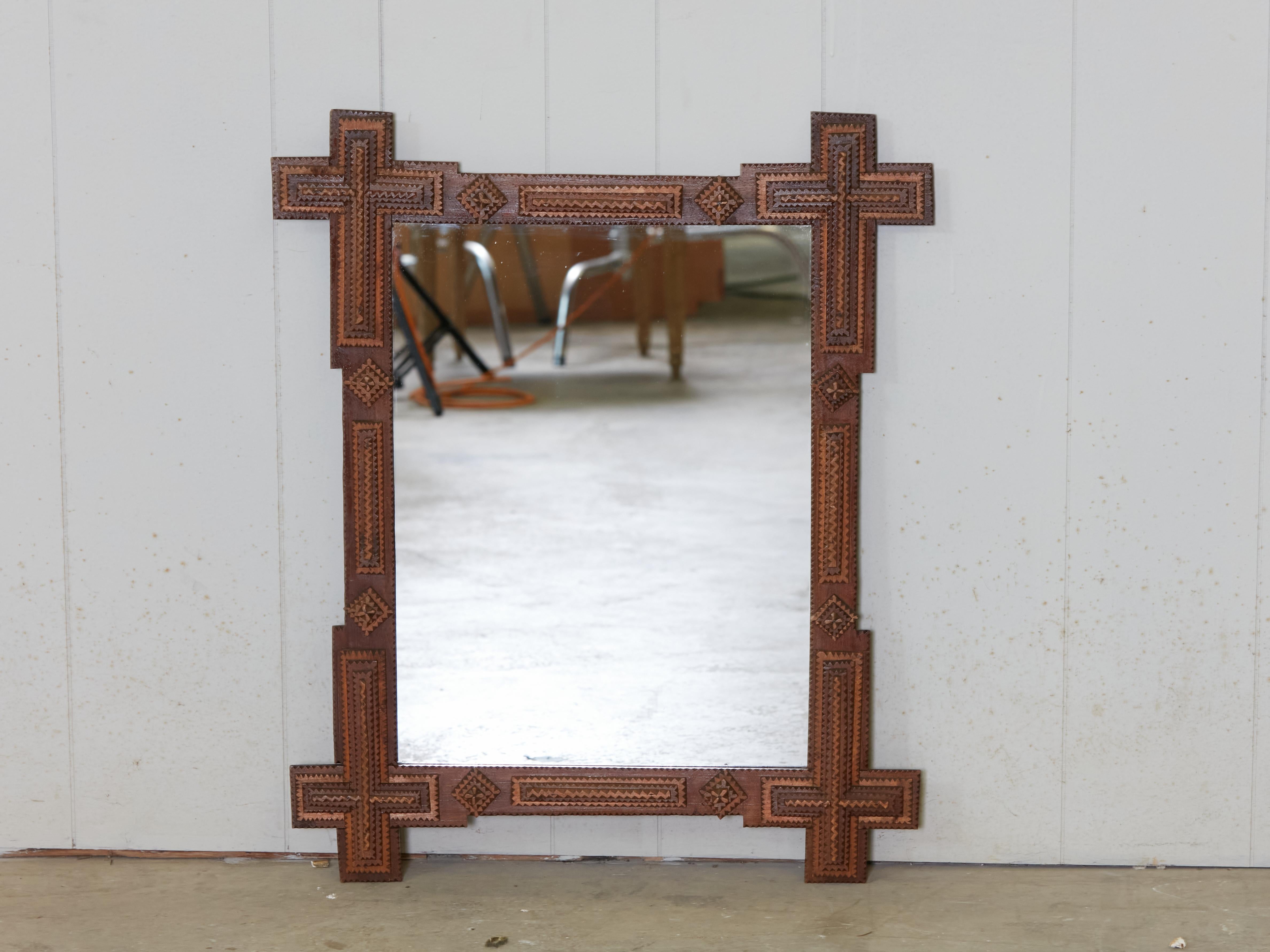 A French Turn of the century Tramp Art hand-carved mirror from the early 20th century, with intersecting corners, raised geometric motifs and brown patina. Created in France during the Turn of the Century which saw the transition between the 19th to