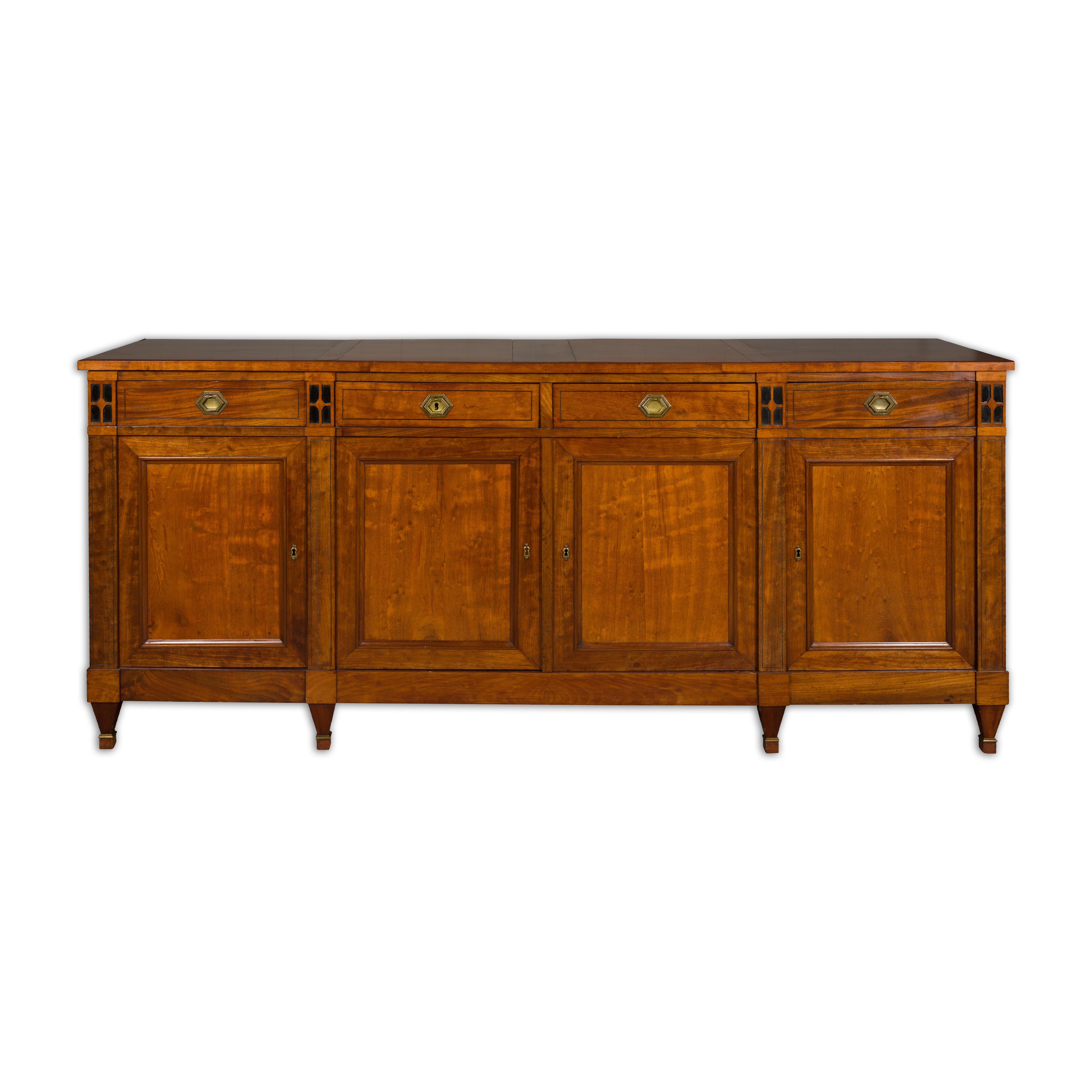 A French Turn of the Century walnut enfilade circa 1900 with four drawers over four doors, ebonized accents, thin banding, brass hardware and tapered feet. Immerse yourself in a symphony of impeccable craftsmanship and elegant design with this