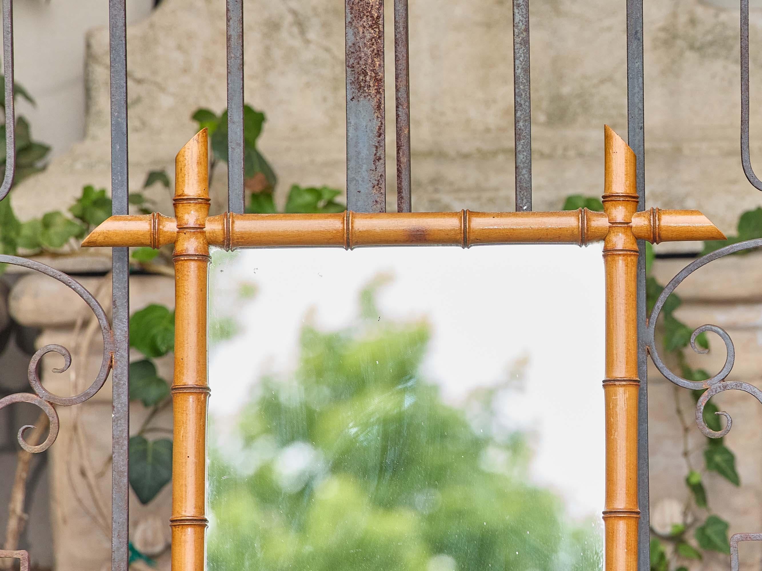 Questo specchio francese in finto bambù del 1900 circa presenta una classica cornice in legno tornito, sagomata in modo da assomigliare a canne di bambù snodate con nodi uniformemente distanziati e finali affusolati che segnano ogni angolo. La calda