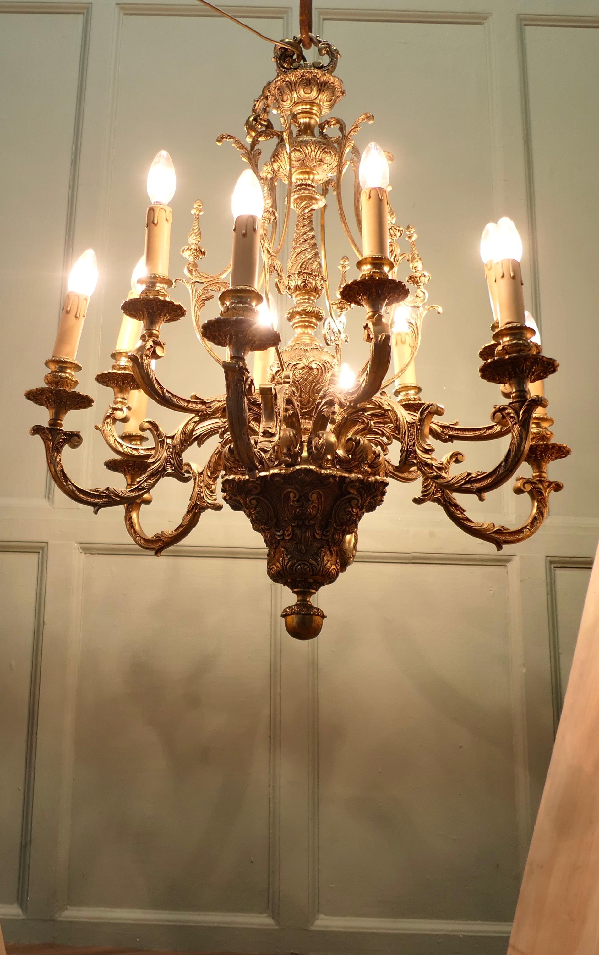 French Twelve Branch Two Tier Gilded Brass Chandelier  

This splendid very large Chateau chandelier is made in Gilded Brass with twelve upward curved arms radiating from an elaborate central baluster column. The chandelier decoration is made up