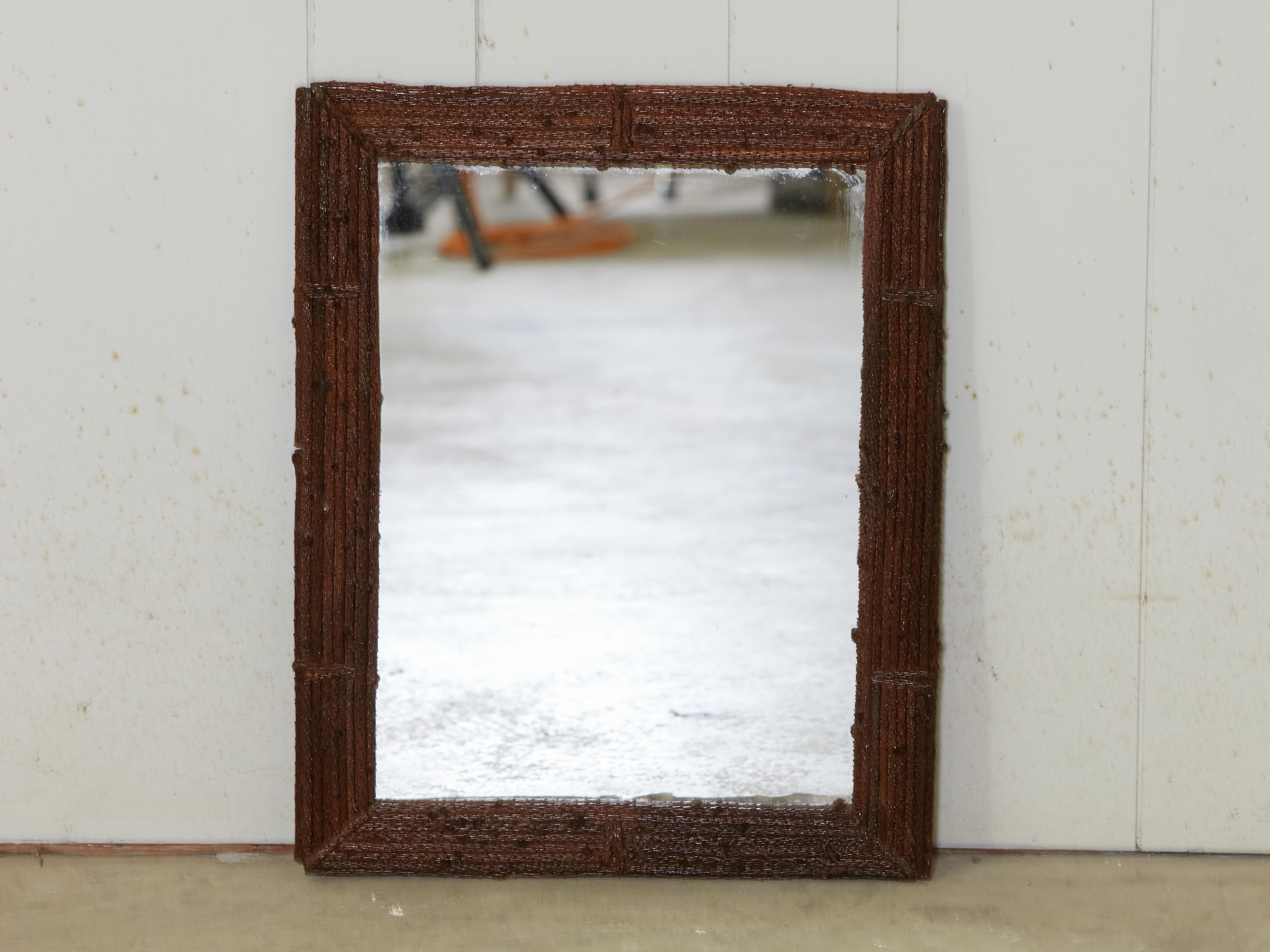 A French wooden Tramp Art twig mirror from the early 20th century, with brown patina and rustic appearance. Created in France during the early years of the 20th century, this Tramp Art mirror charms us with its simple lines, rustic character and