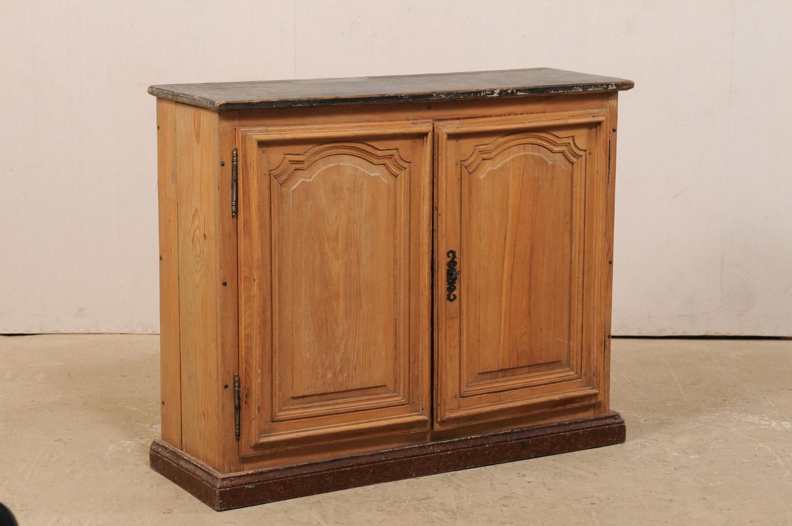 Un buffet francese a due ante in legno con piano dipinto del XIX secolo. Questo mobile antico proveniente dalla Francia presenta un piano di forma rettangolare su una cassa dotata di un paio di ante a pannello singolo ben intagliate, ed è sollevato