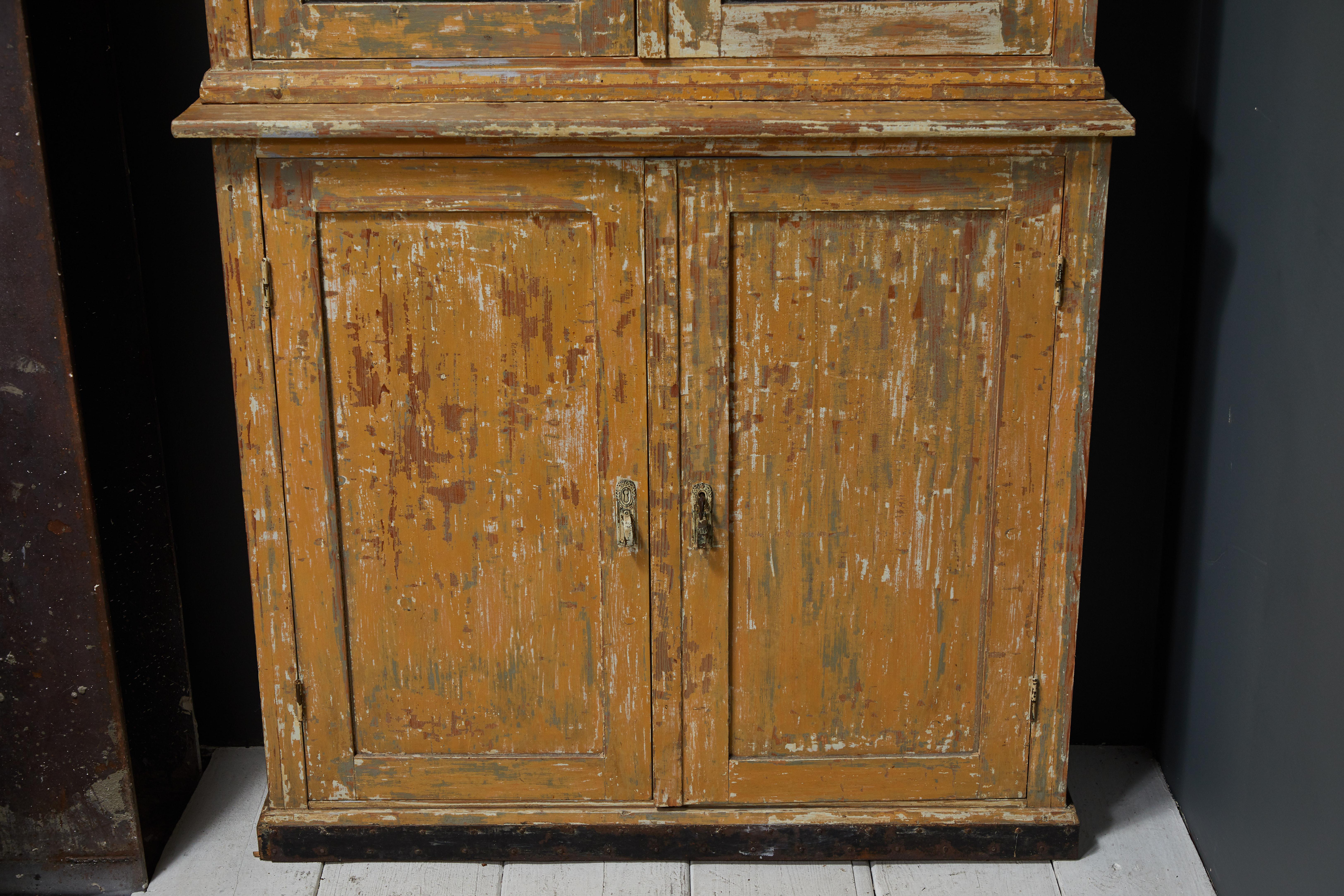 French two piece china cabinet hutch with glass doors. The cabinet offers original weathered finish.