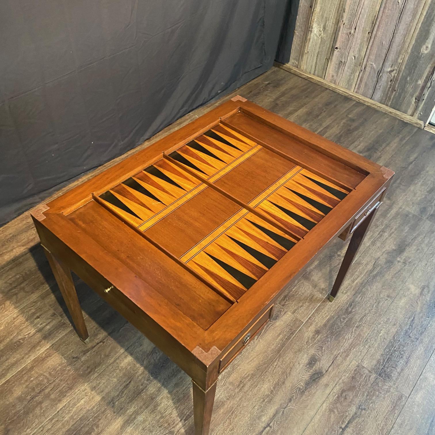 A French Louis XVI style Tric Trac game table of solid walnut, bronze mounts, square tapered legs with fluted columns and bronze sabots. Crafted from rich walnut and adorned with walnut veneer, it embodies elegance and sophistication with provincial