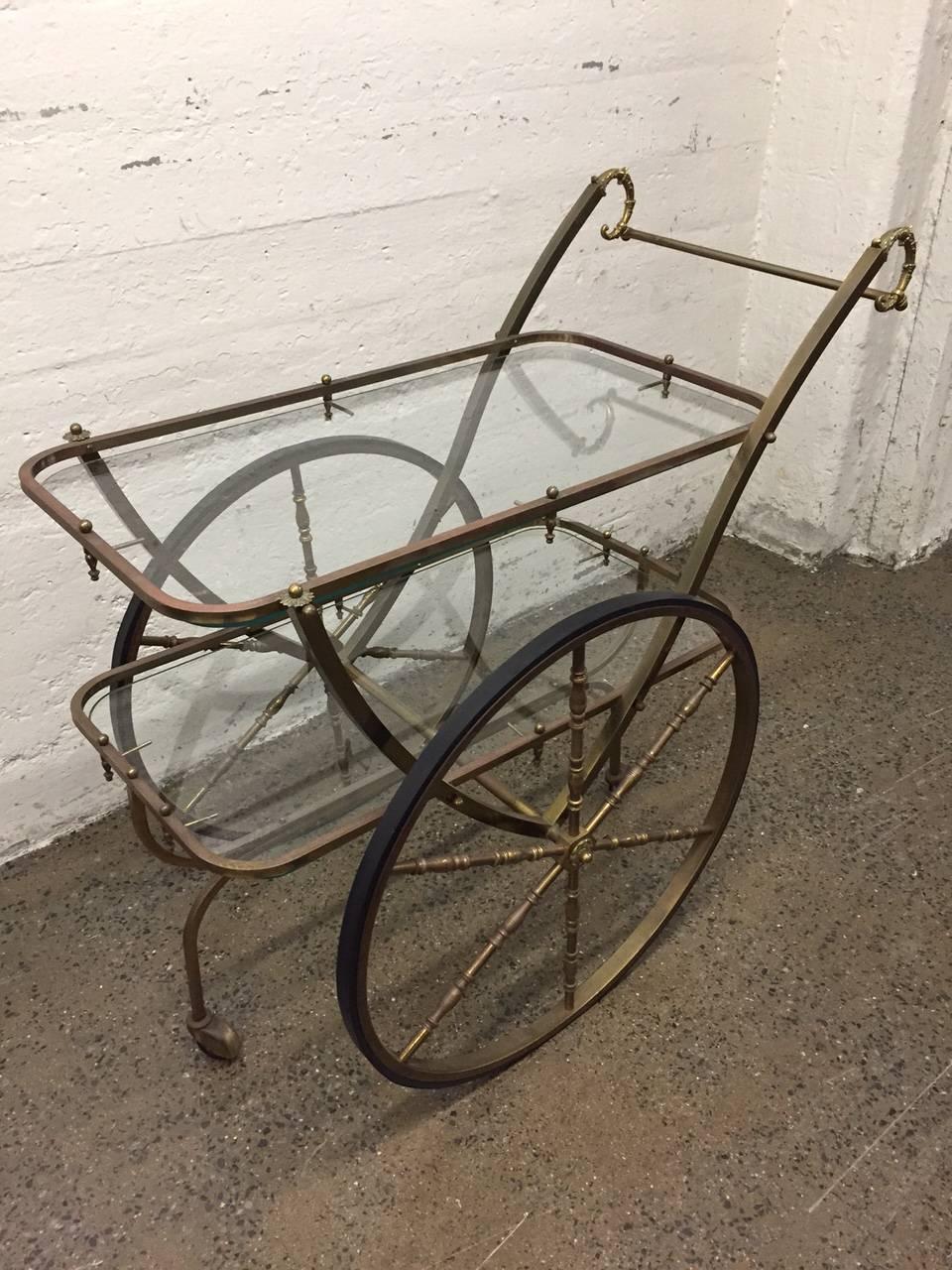 French, two-tier glass and brass bar cart. Large wheels and has original patina.