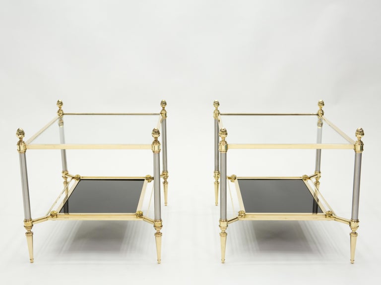 These beautiful two-tier end tables by French design house Maison Jansen were created with solid brass, gunmetal, and typical French neoclassical brass pine cones in the early 1970s. The black opaline glass bottom shelf is smooth, and provides an