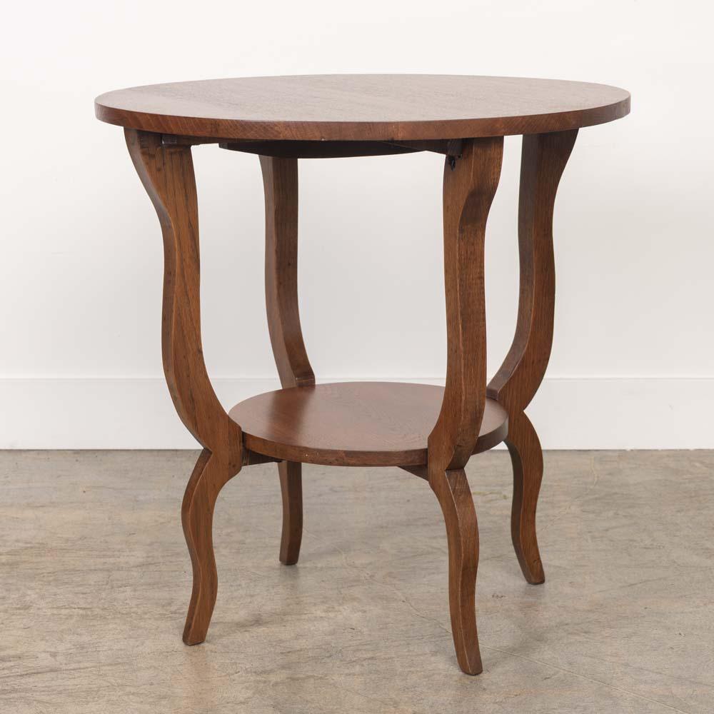 Ravissante table d'appoint à deux niveaux en chêne sculpté, France, années 1940. Plateau circulaire avec étagère inférieure et quatre pieds courbes sculptés. La finition récemment rafraîchie présente une belle patine d'âge. Parfait entre deux