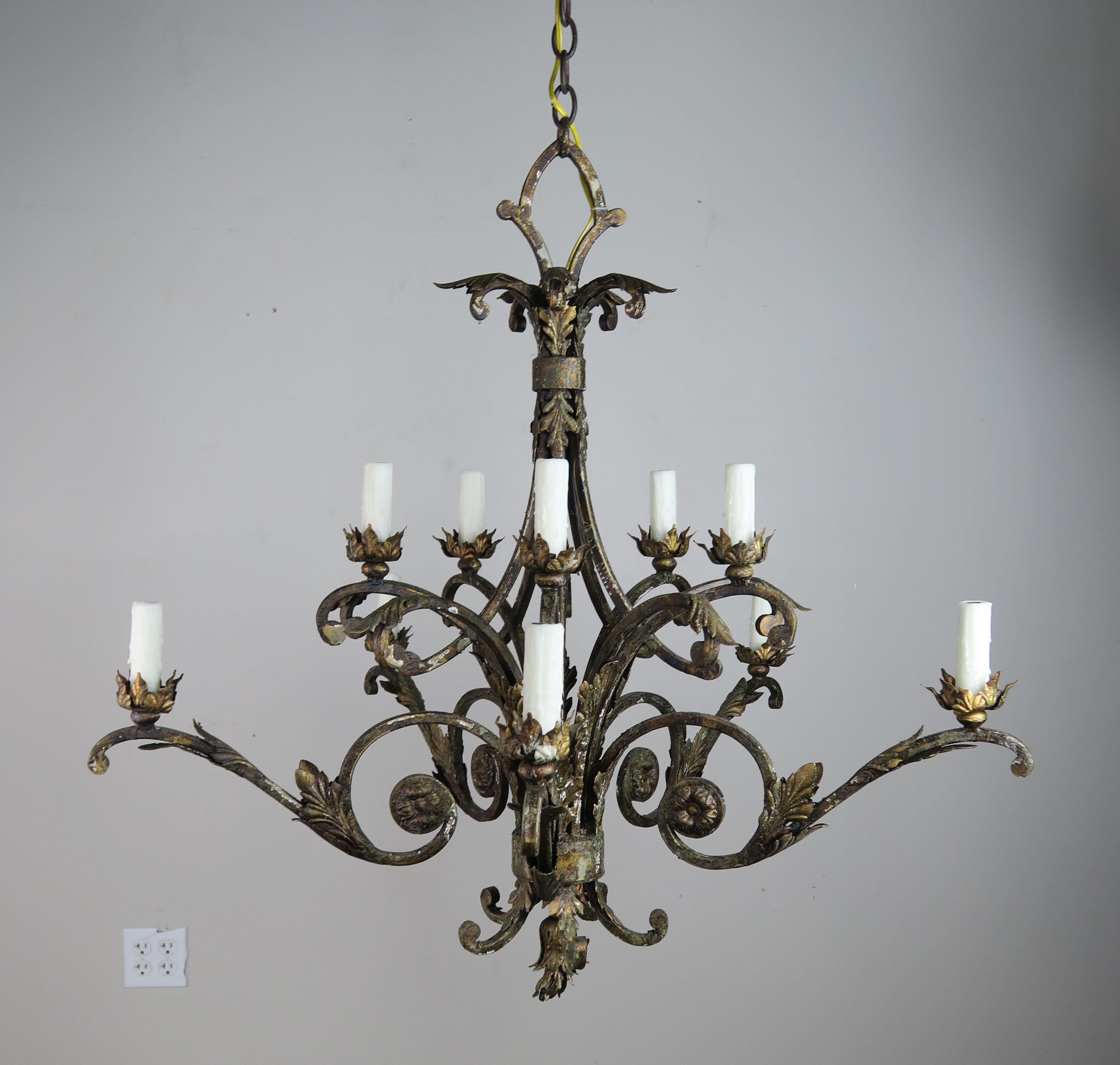 French two-tier (10) light wrought iron chandelier newly rewired with drip wax candle covers and includes chain and canopy. Small remnants of paint and gold leaf can be seen in the finish and give the fixture some subtle luster.