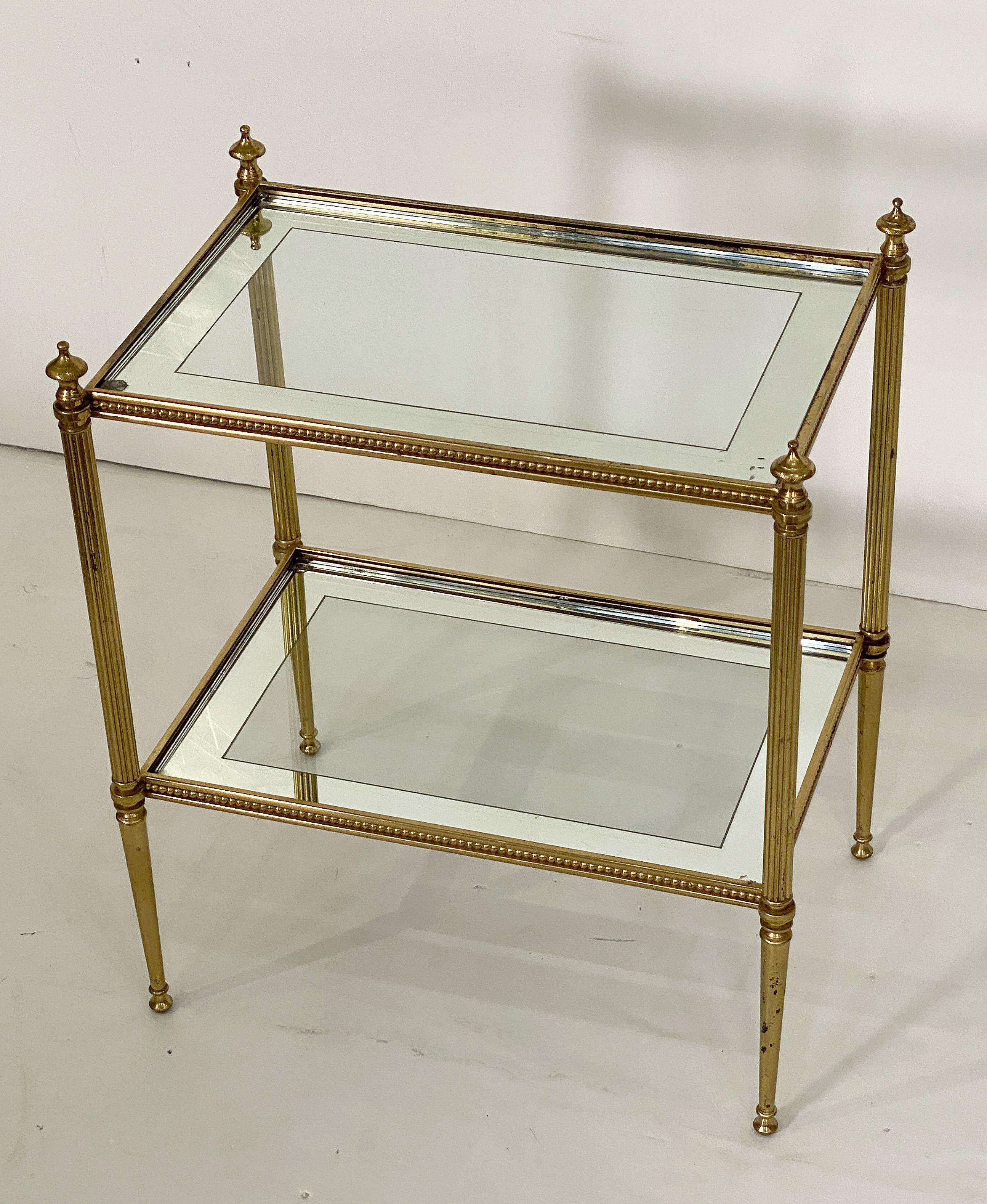 A fine French two-tiered rectangular cocktail side or end table of brass, from the Mid-Century Modern era, attributed to Maison Bagues. 

Featuring reeded legs topped with finials and tapering ends - the upper and lower tiers with inset