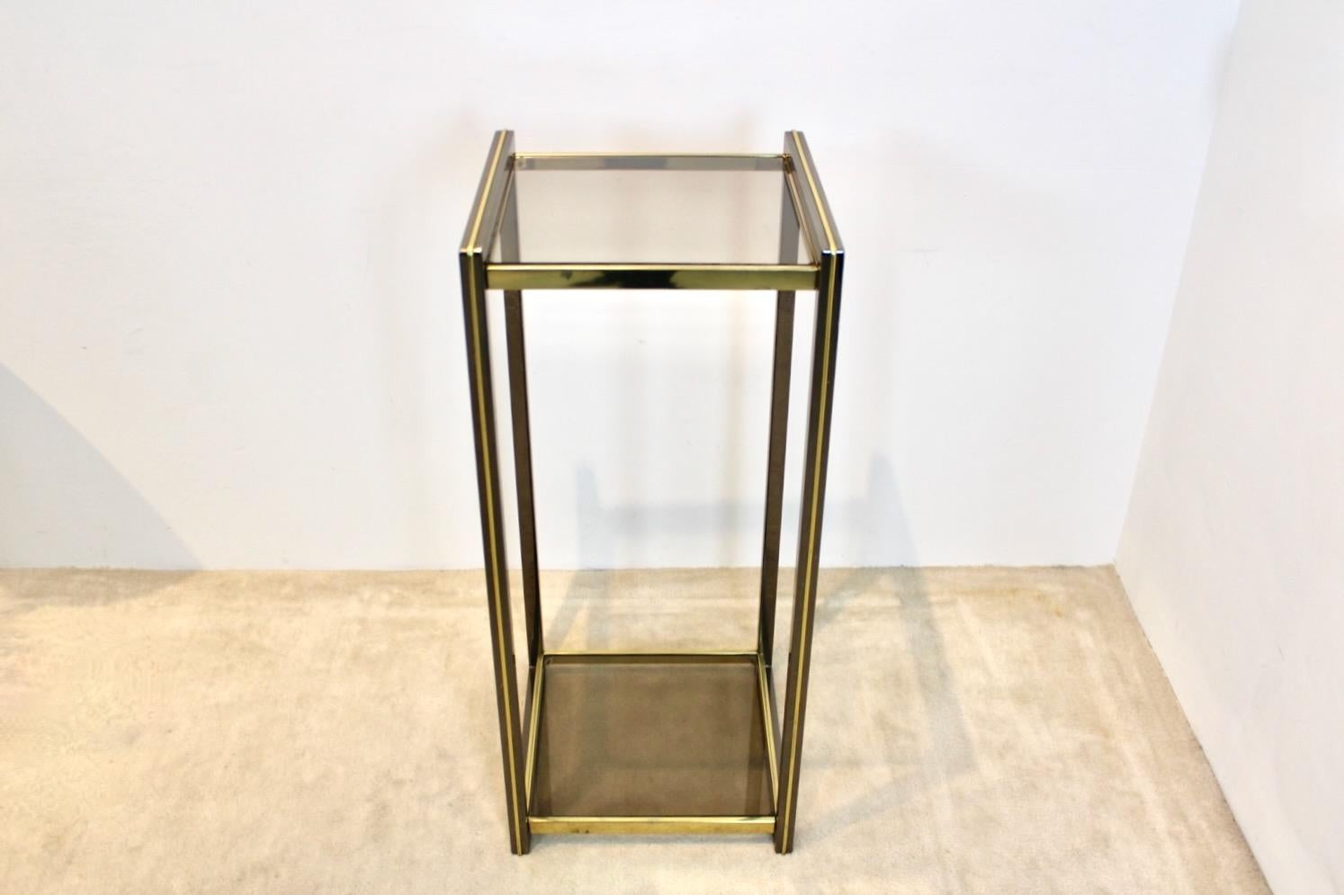 Bellissimo tavolo consolle con piedistallo in ottone a due livelli realizzato in Francia negli anni '70. Creato da Maison Jansen. Patina unica e piano in vetro fumé di grande classe in stile hollywoodiano. Design semplice ma piacevole e pratico,