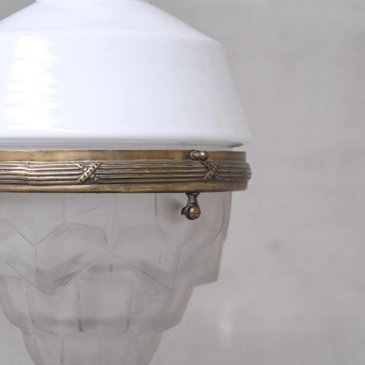An unusual shaped two tone glass pendant light.

France, c1920s.

Brass rim and gallery.

Opaline glass top, opaque geometric stepped shaped base.

No chain or rose was retained, however they are easy to source online.

Location: Belgium