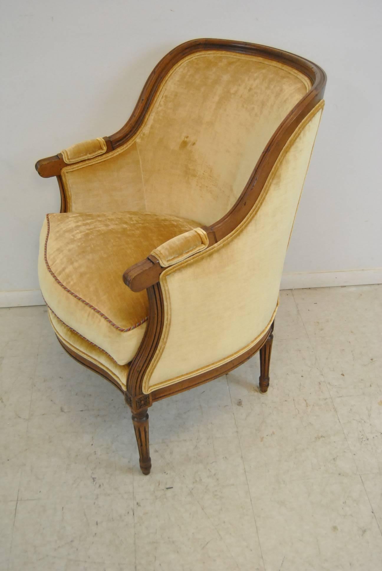 A fabulous French style upholstered bergere chair by Isenhour Furniture. This charming chair features a finely carved hardwood frame, a classic gold toned fabric and a removable down cushion. It is in very good to excellent condition. The dimensions