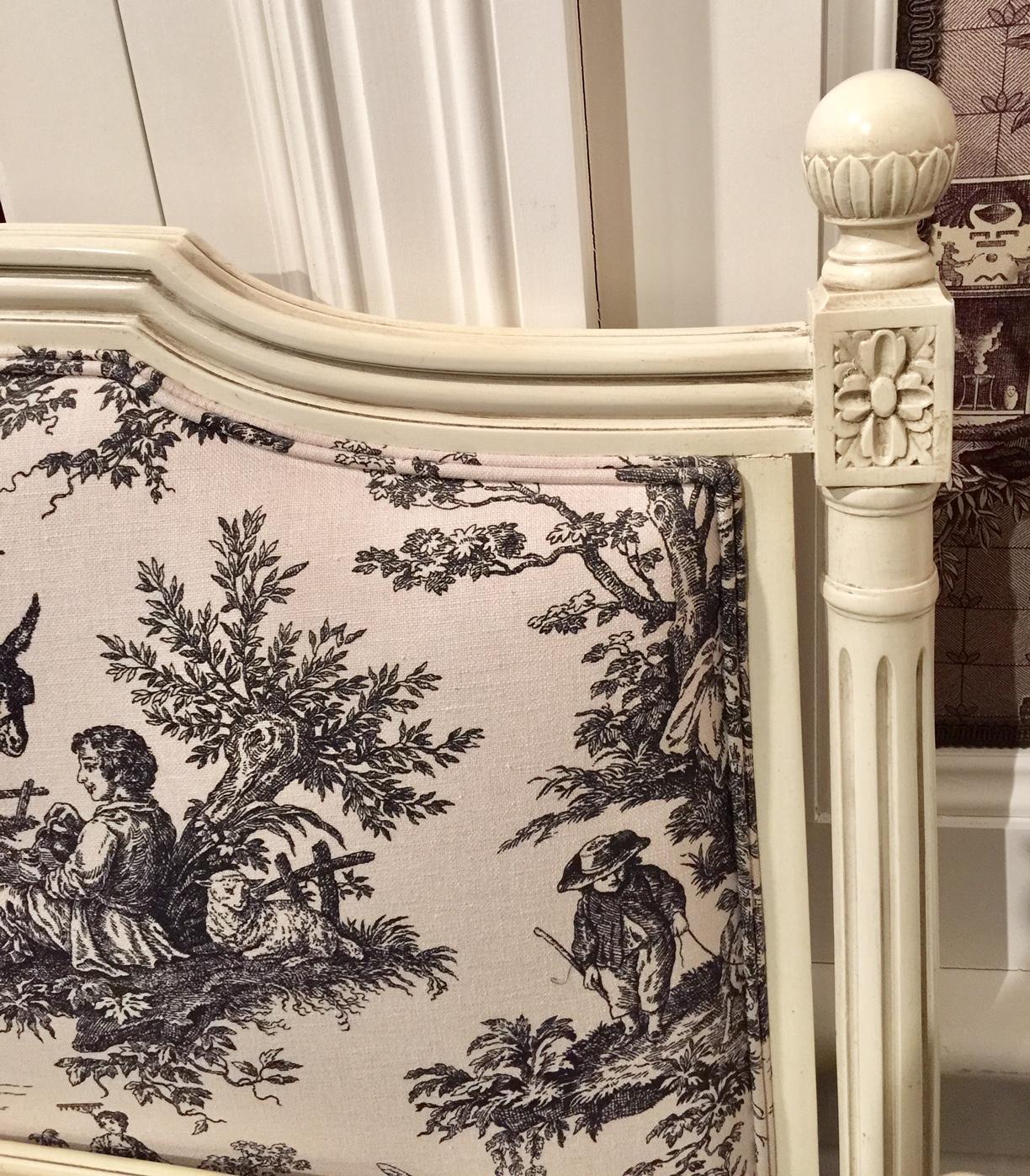 French upholstered double bed frame in the Louis XVI style, cream patinated wood. The pretty French bed features upholstered head and foot boards covered with Toile de Jouy in black on cream background. The cotton fabric is printed in a replica of