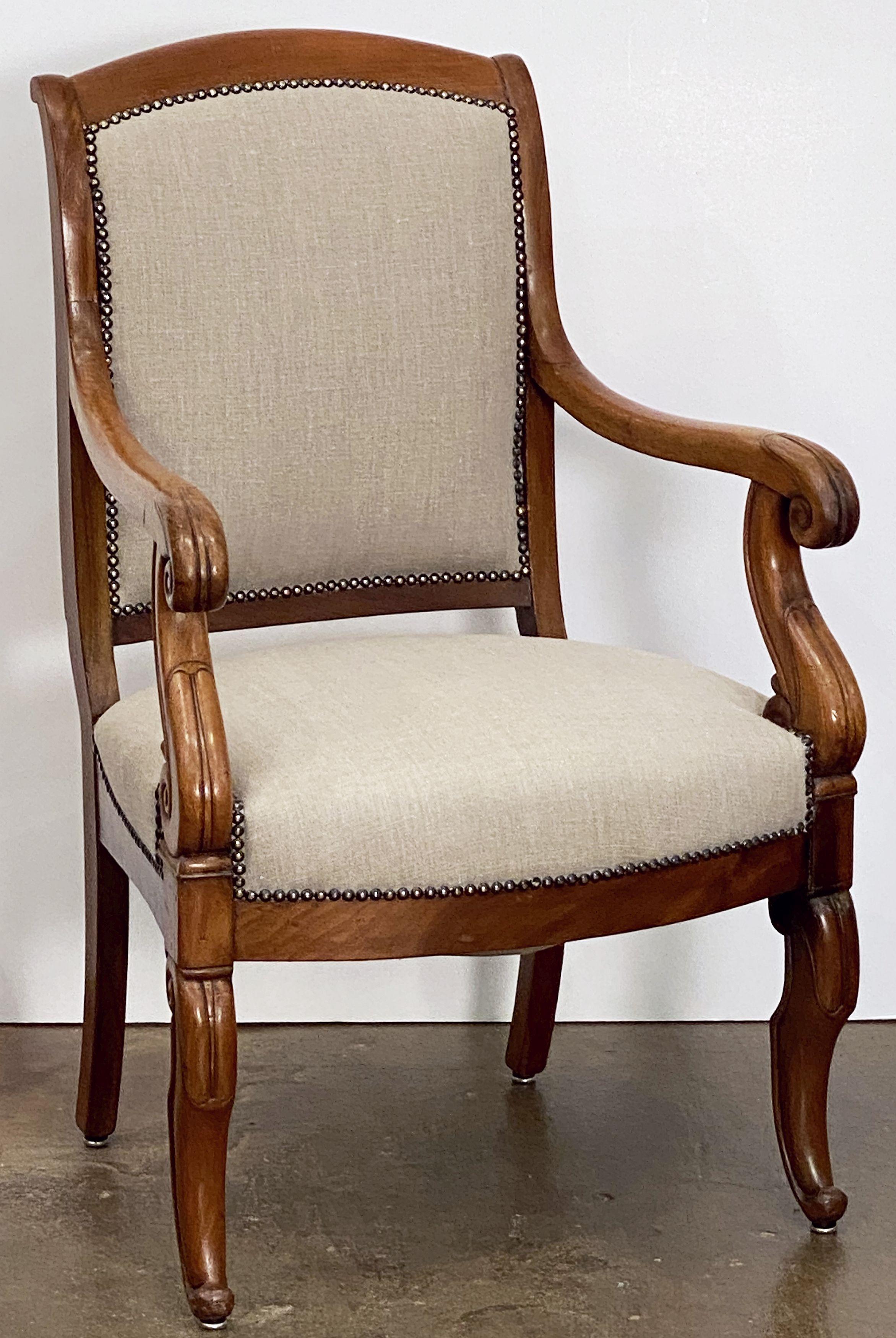 A fine French fauteuil desk or salon chair with carved detail to the frame, scroll arms, on raised legs, circa 1900.

Featuring a comfortable seat re-upholstered in plain linen fabric, with brass nail-head decorative trim.

Dimensions: H 36 3/4