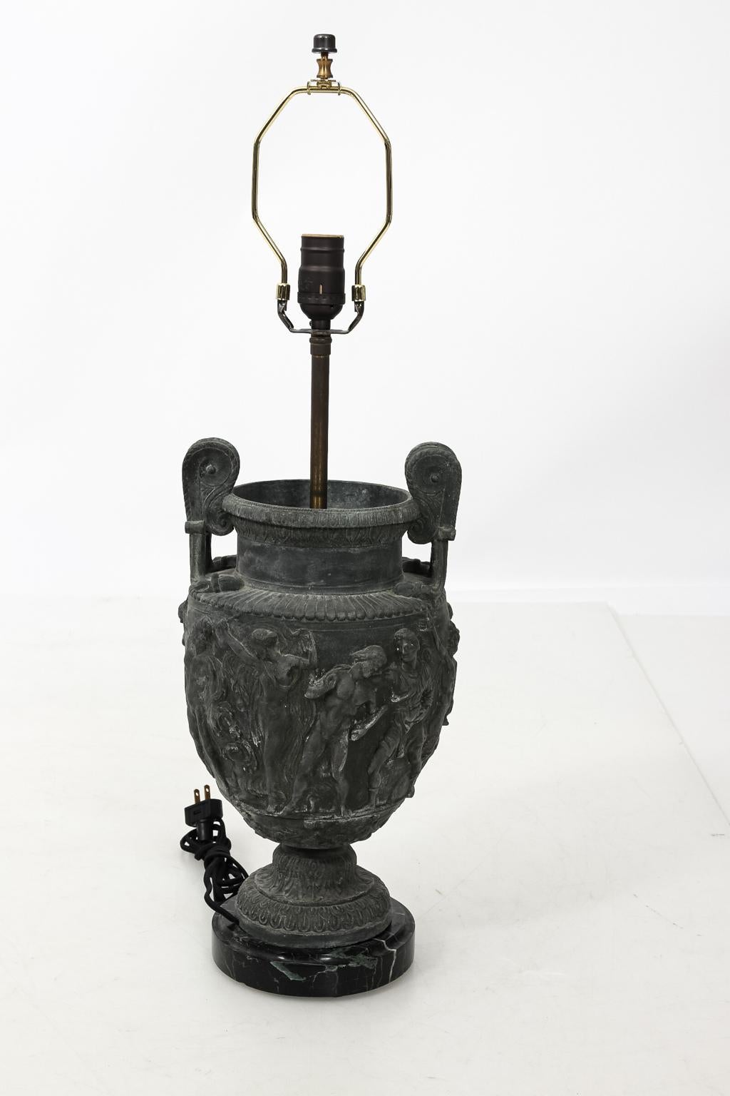 French neoclassical style urn shaped lamp in metal with classical figures on the body, circa 19th century. Shades not included. Please note of wear consistent with age including patina and minor oxidation.